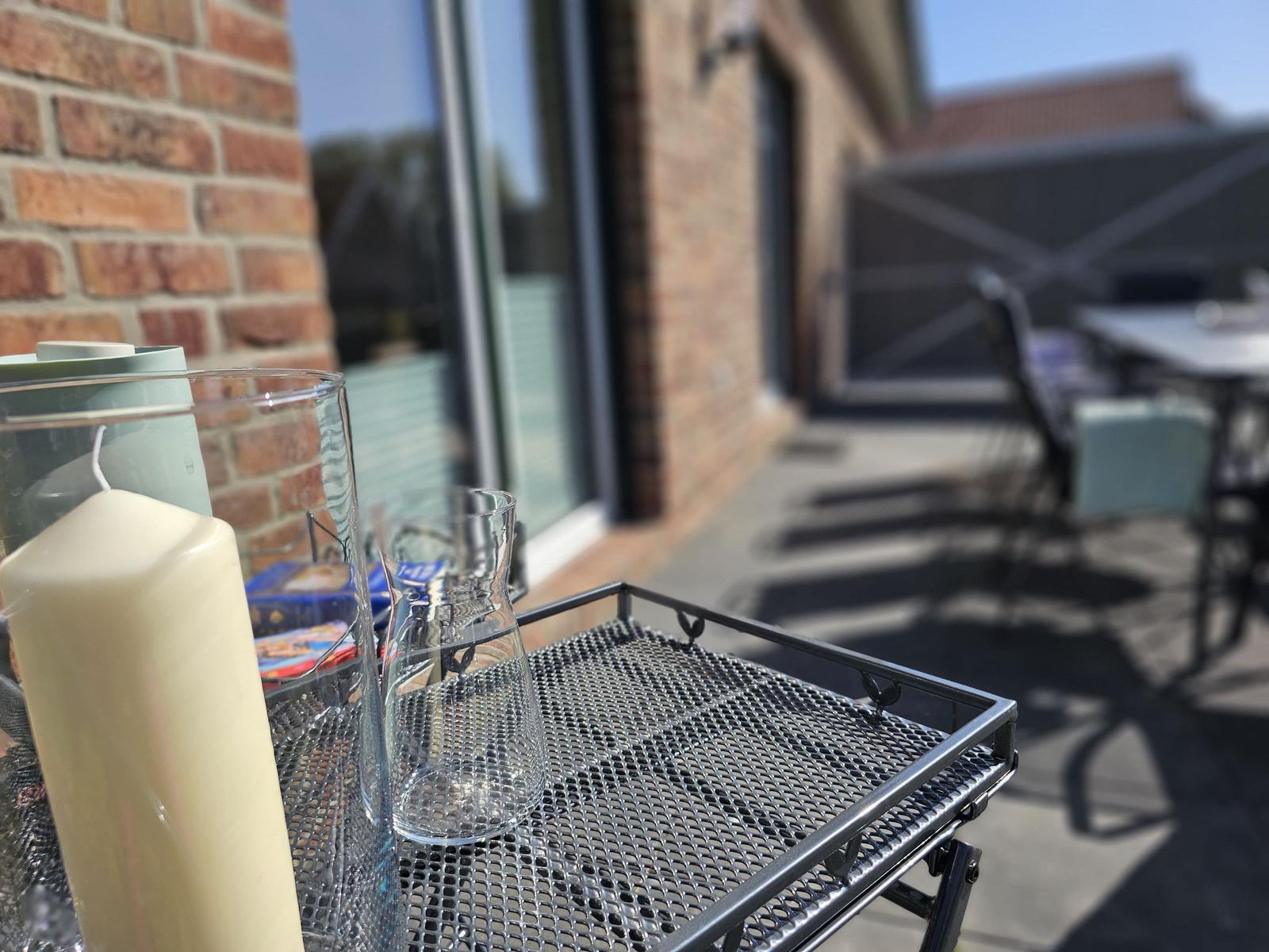 Außenbereich mit Tisch, Stühlen und Kerze auf Metalltablett.