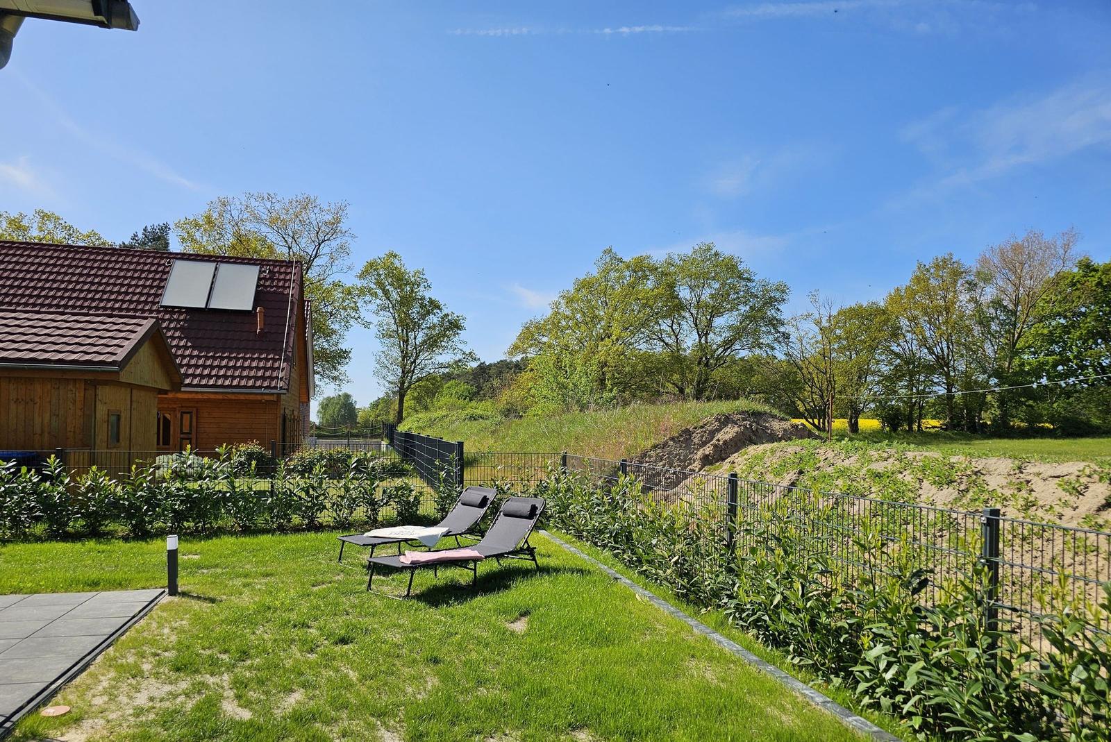 Haus mit Garten, Sonnenliegen und Blick auf Wald.