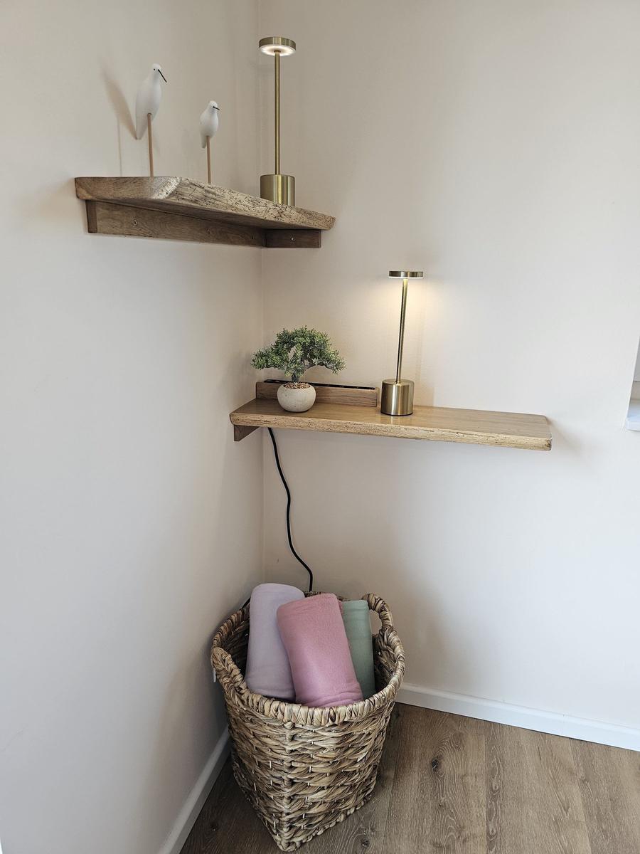 Ecke mit Holzregalen, Lampen und Korb mit Handtüchern.