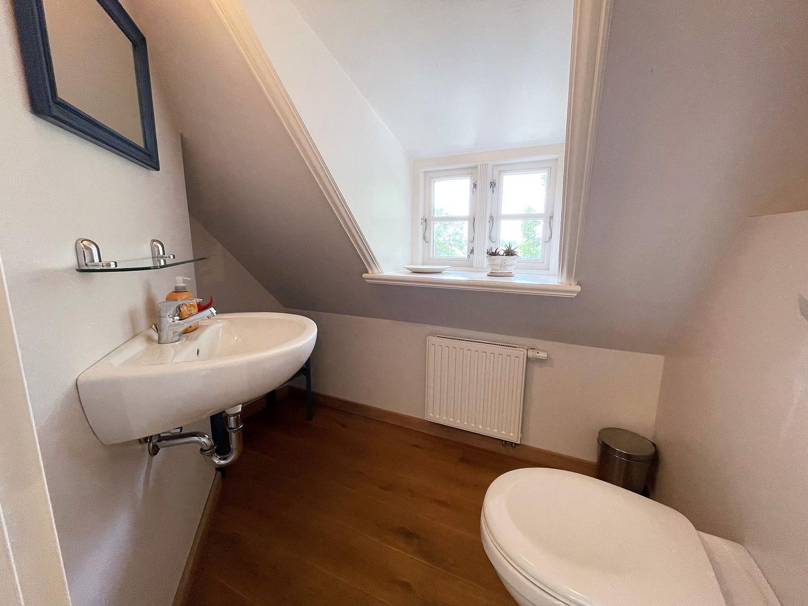 Badezimmer mit Waschbecken, Toilette und Fenster