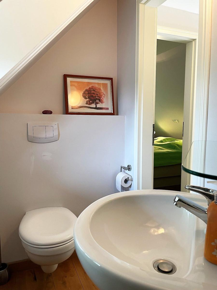 Badezimmer mit Waschbecken, Toilette und Bild an der Wand