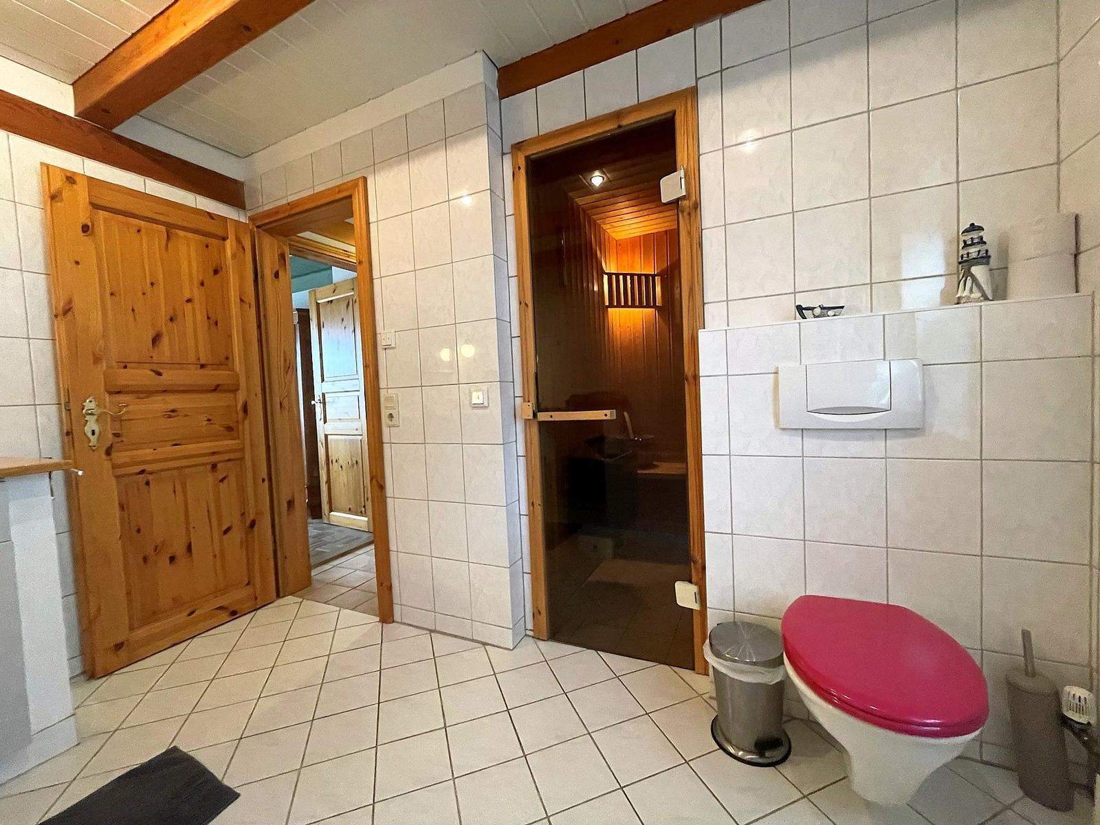 Badezimmer mit Toilette, Sauna und Holztüren.