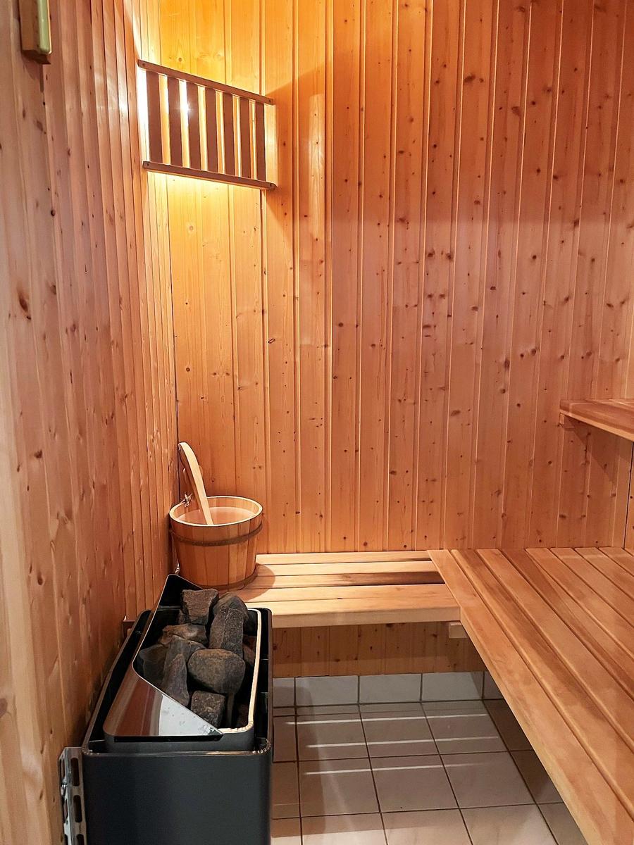 Sauna mit Holzbank, Eimer und Steinkasten.