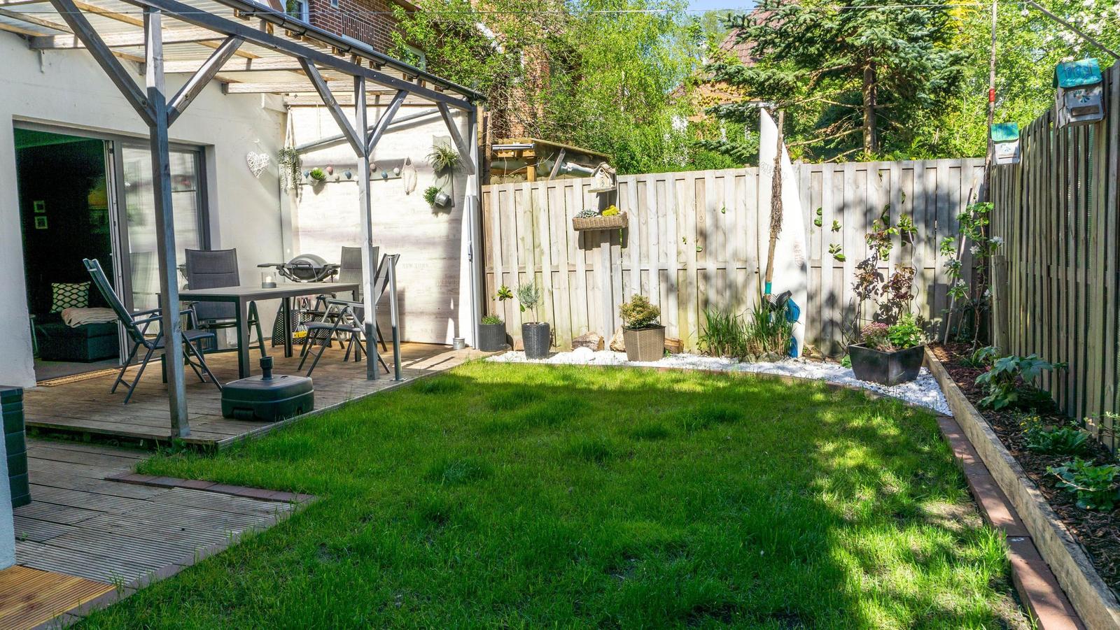 Hinterhof mit Grillplatz, Terrasse und grünem Rasenbereich.