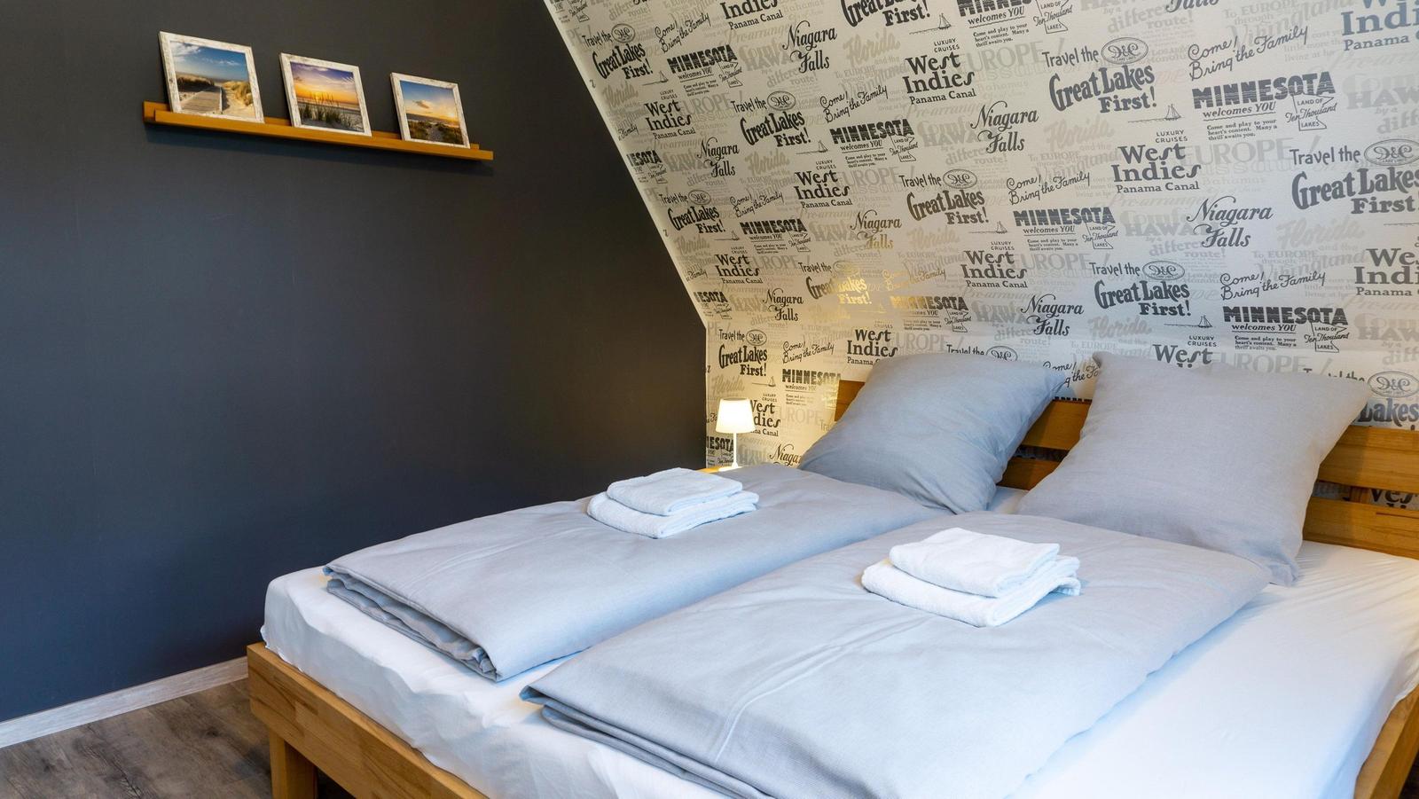 Schlafzimmer mit Bett, dekorativer Tapete und Bilderrahmen an der Wand.