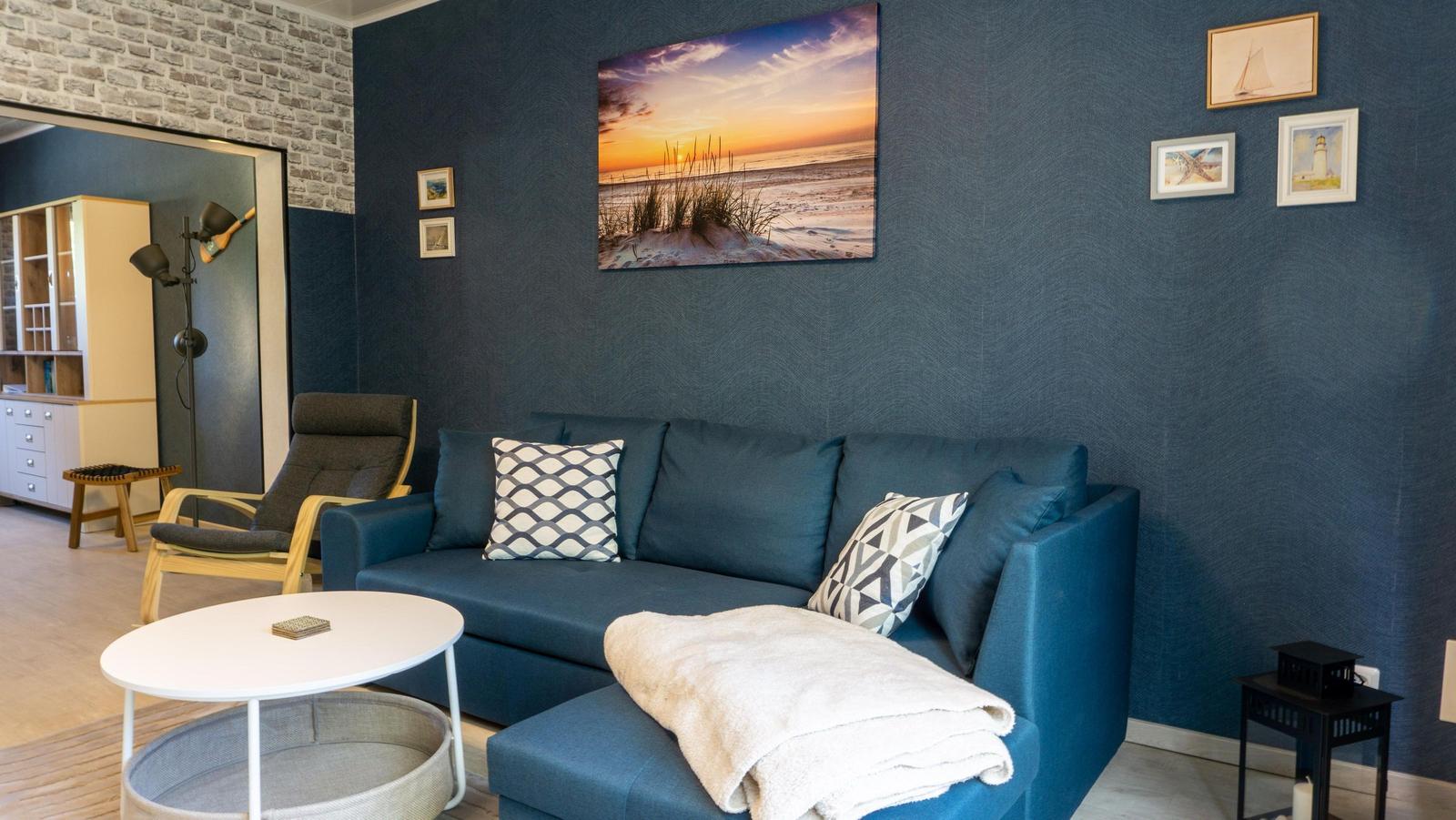 Ein Wohnzimmer mit blauem Sofa, Wandbild und dekorativen Kissen.