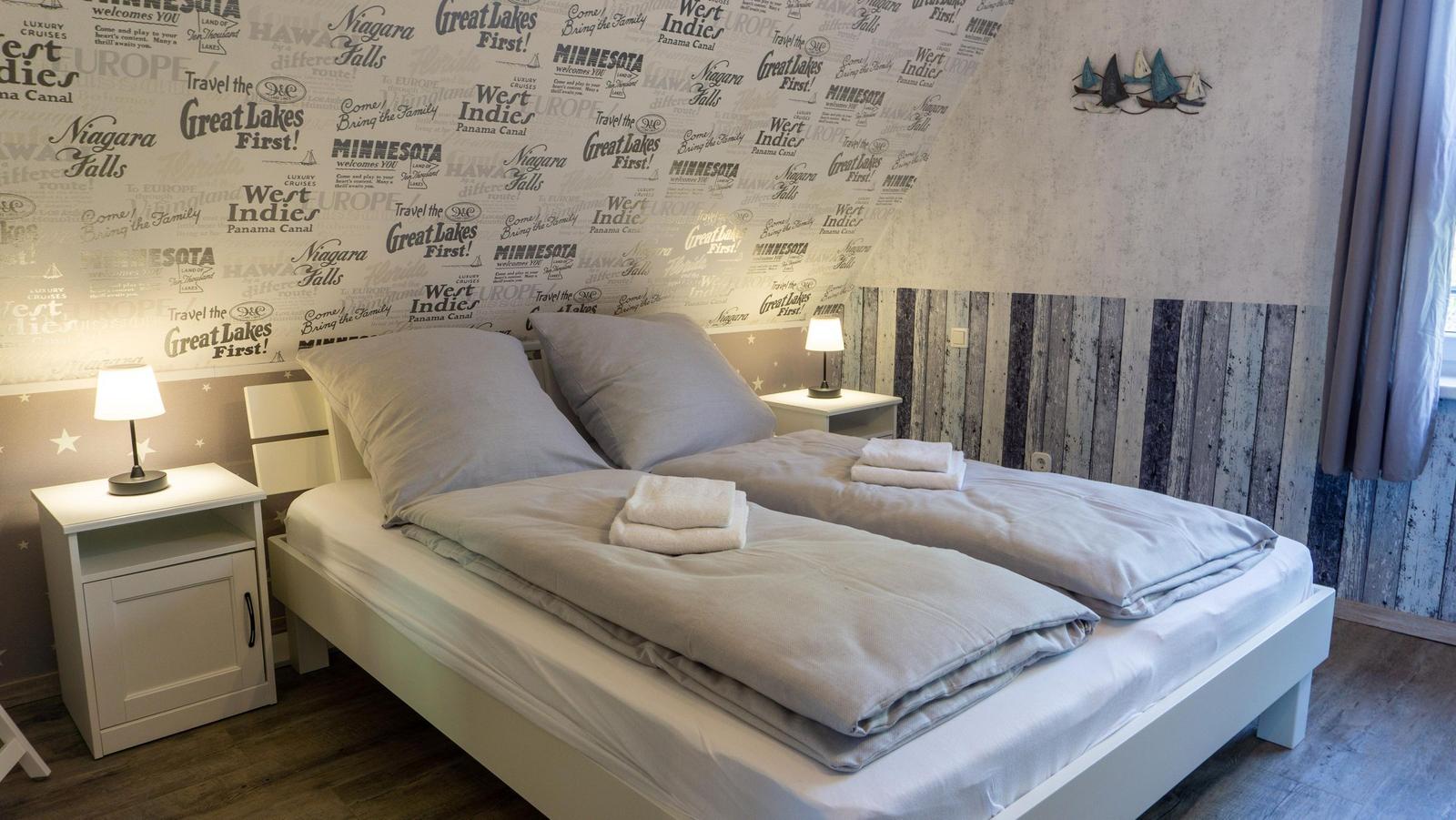 Schlafzimmer mit Doppelbett, zwei Nachttischen und dekorativer Wandtapete.