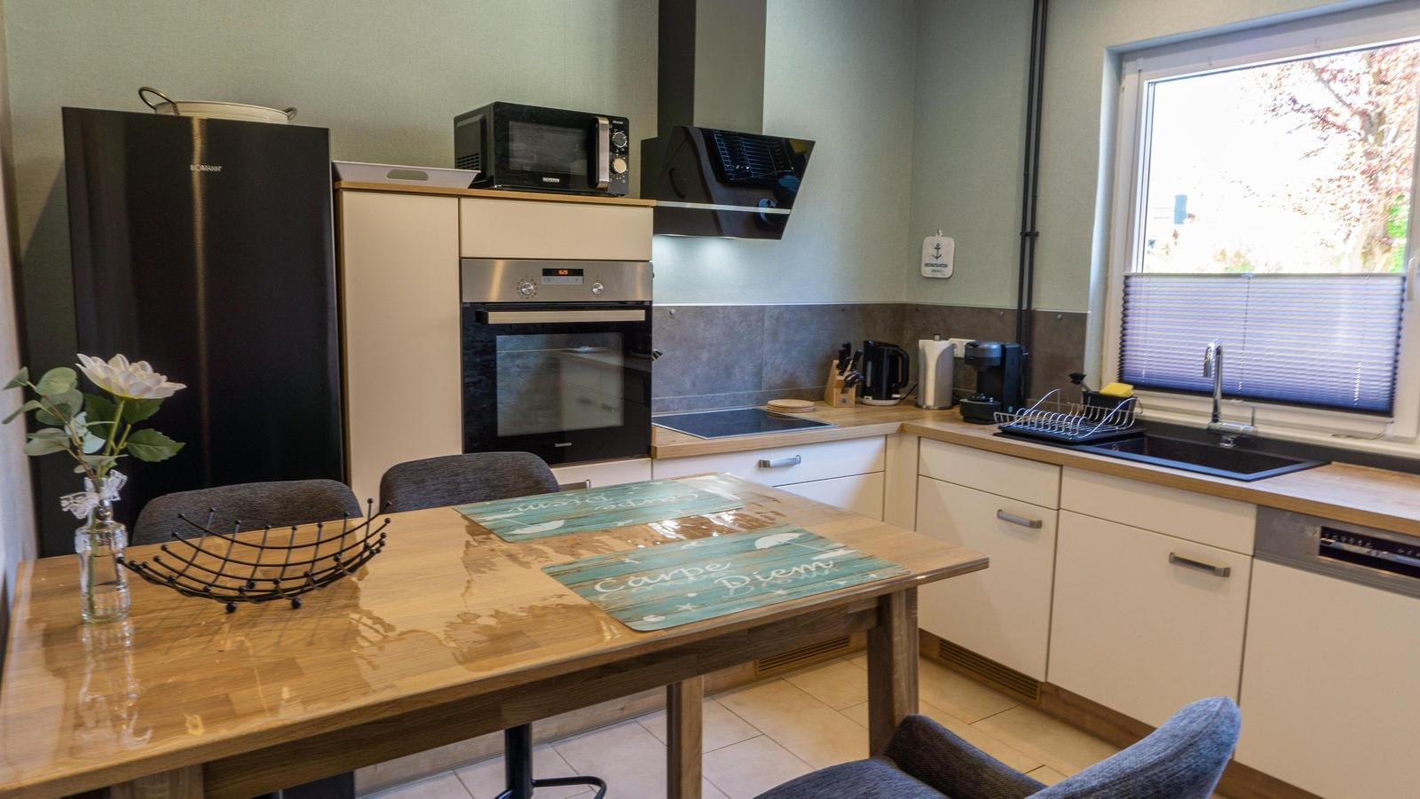 Küche mit Essbereich, Kühlschrank, Herd und Fenster.