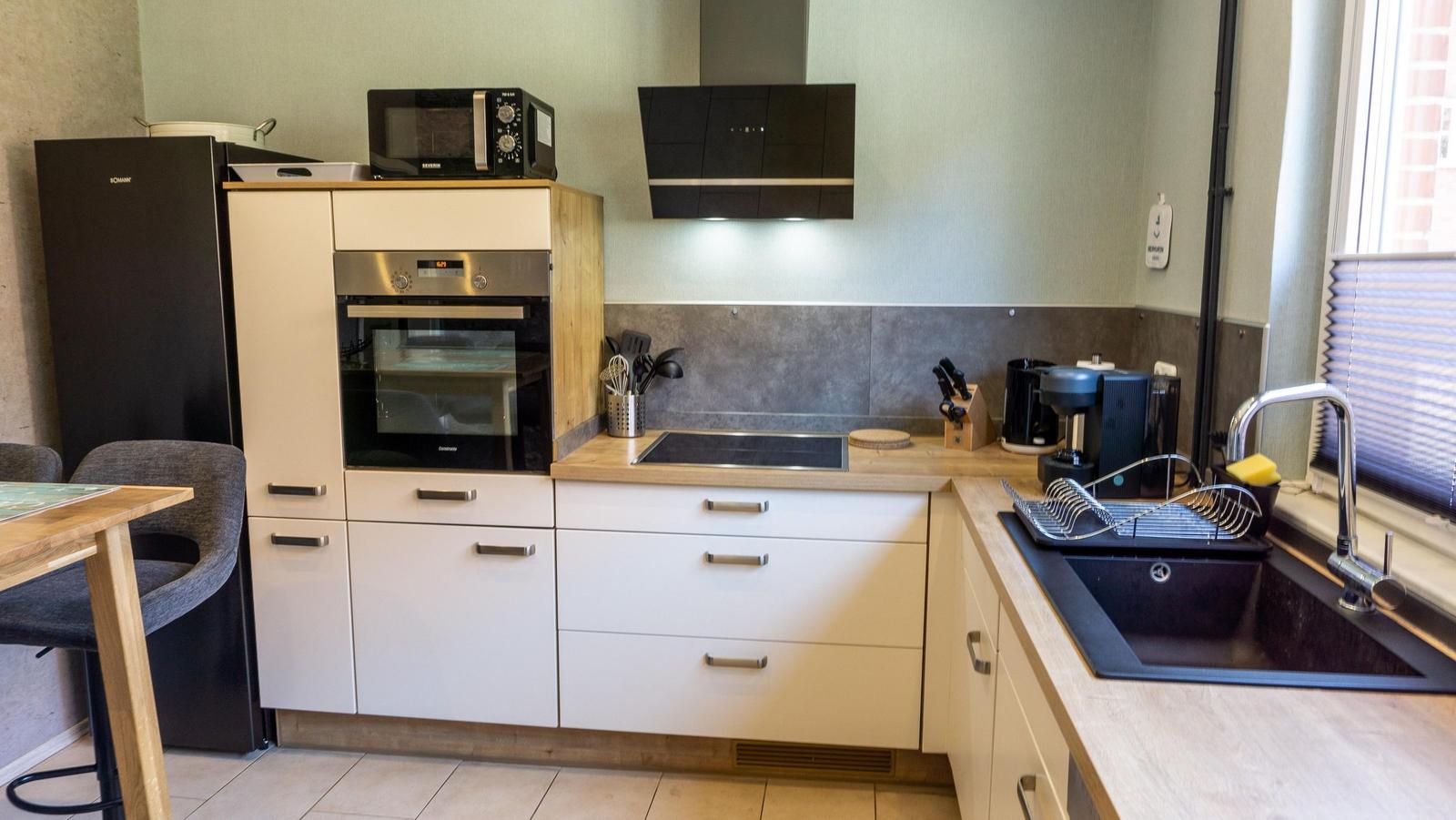 Küche mit Kühlschrank, Herd, Spüle und Fenster.