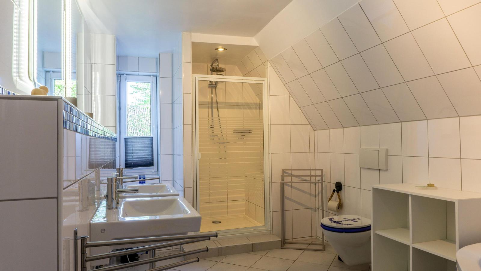 Badezimmer mit Dusche, Toilette und Waschbecken unter schrägem Dach