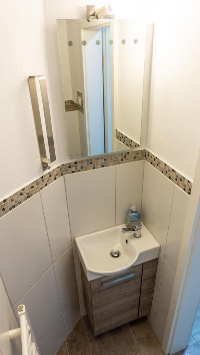 Badezimmer mit Waschbecken, Spiegel und Handtuchhalter.