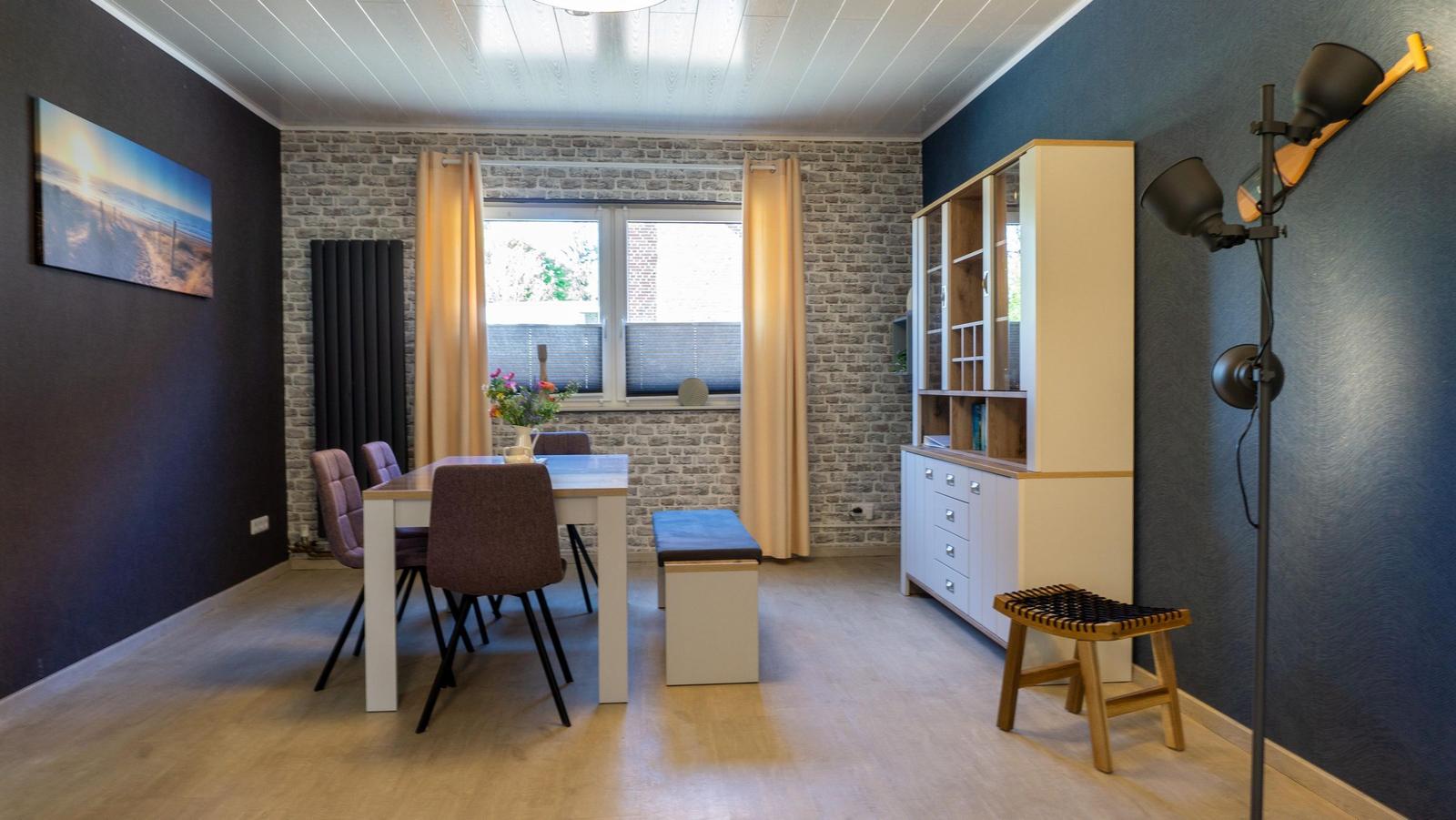 Esszimmer mit Tisch, Stühlen und Regal an der Wand.