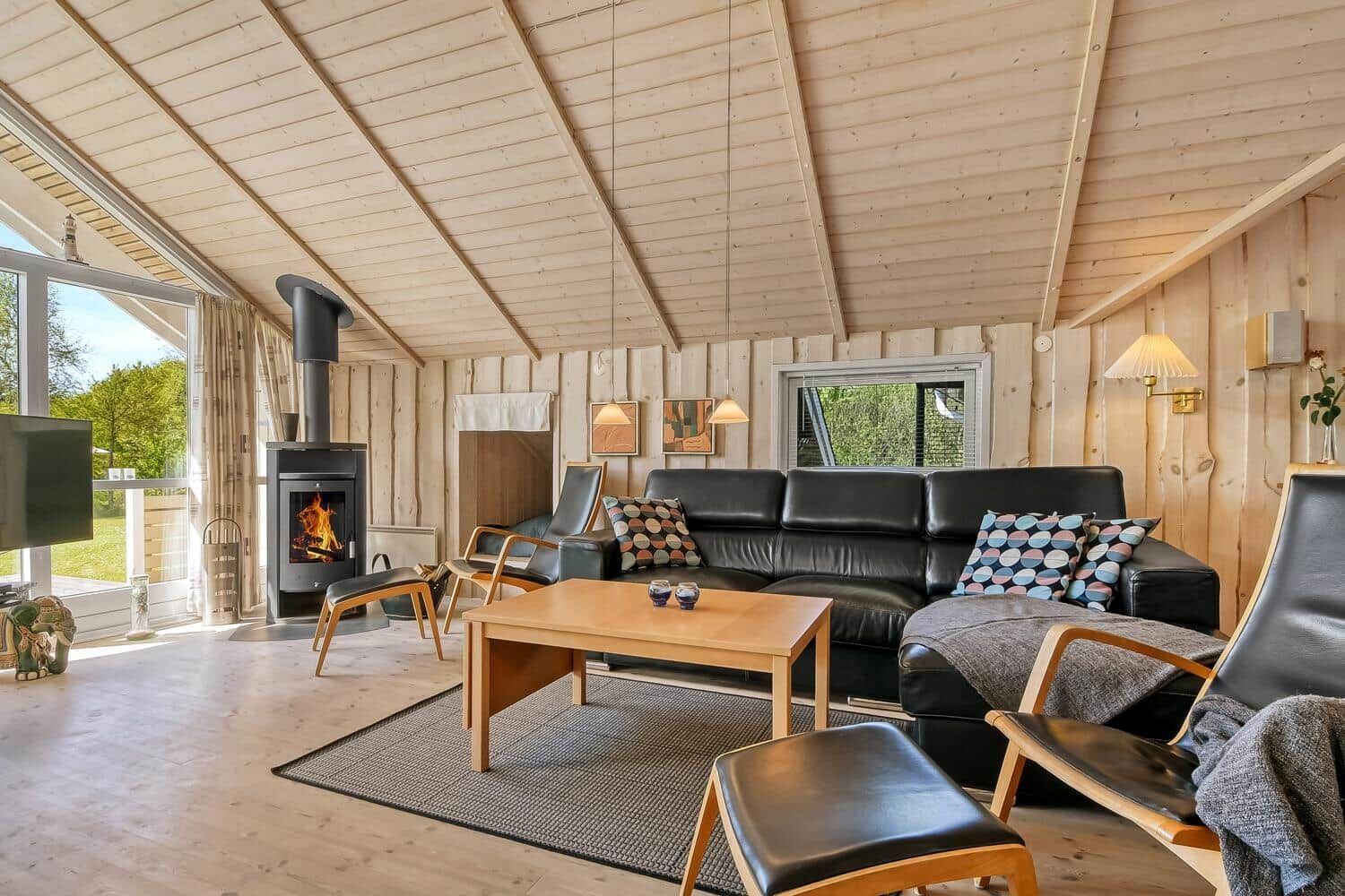 Wohnzimmer mit Holzwand, Sofa, Kamin und Fensterblick.