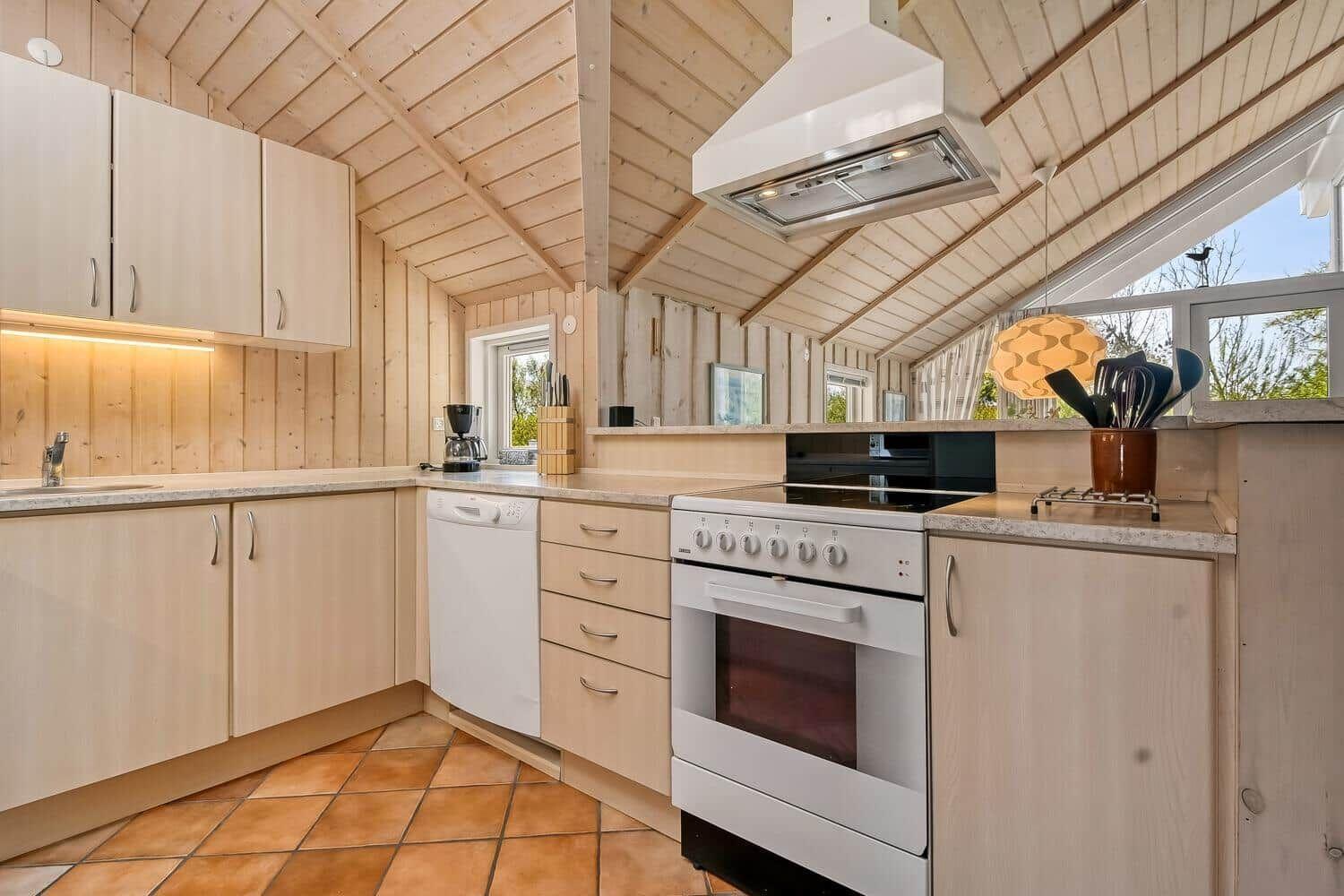Küche mit Holzwand, weißen Geräten und Fensterblick