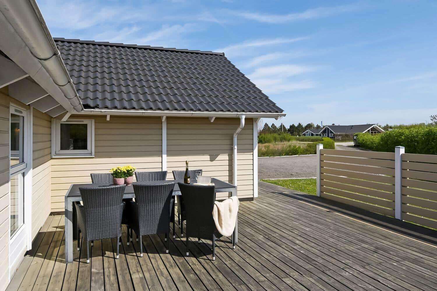 Terrasse mit Tisch und Stühlen vor einem Haus mit Holzveranda.