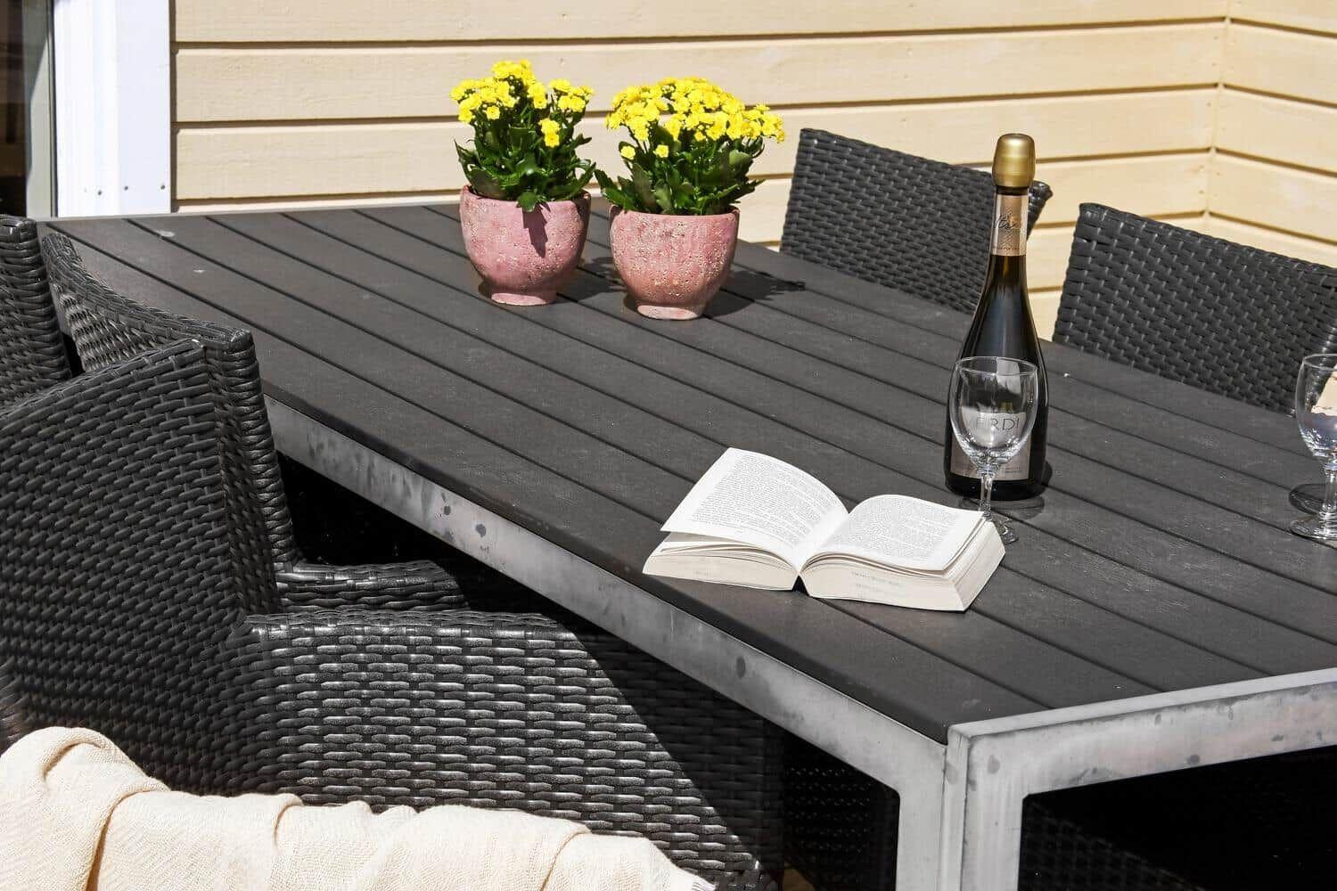 Außenbereich mit Tisch, Stühlen, Blumen und Weinflasche.