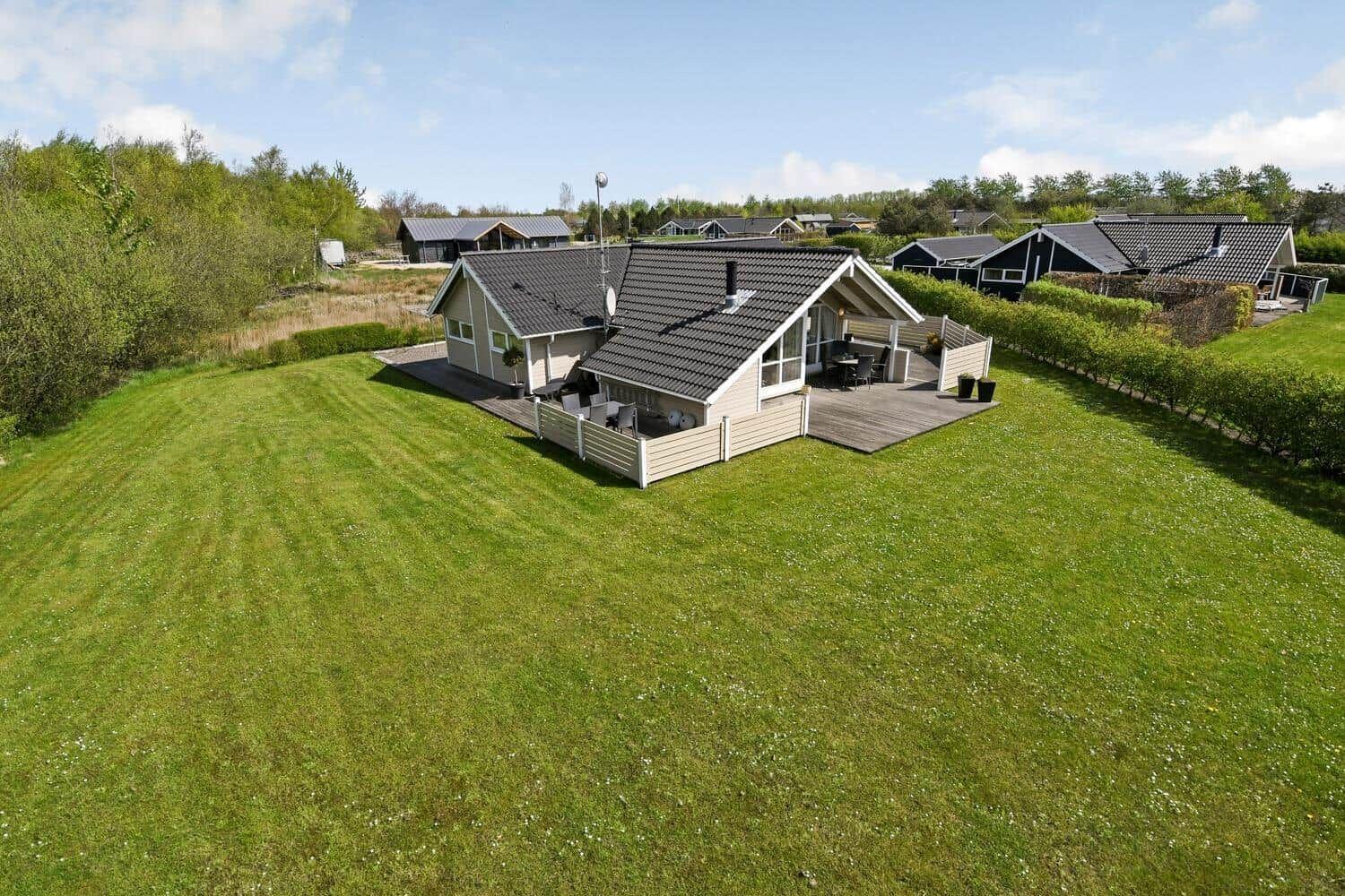 Haus mit Terrasse und großem Garten. Umgeben von Grünflächen und Bäumen.