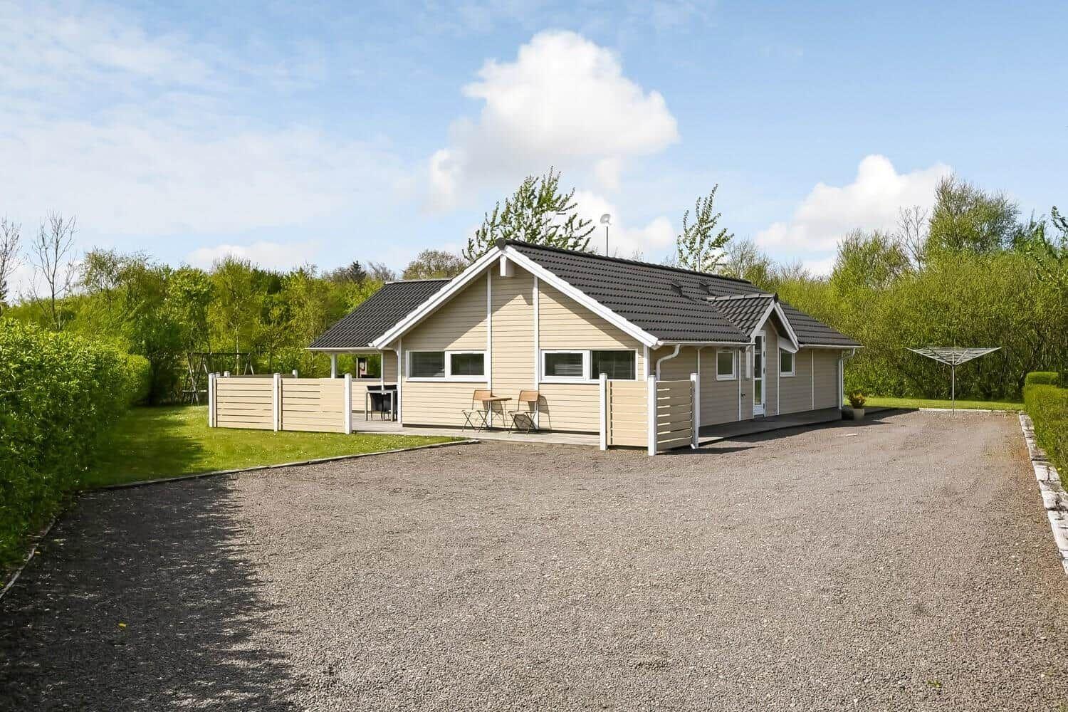 Ein Haus mit Terrasse, Garten und Grillplatz. Umgeben von Bäumen und Grünflächen.
