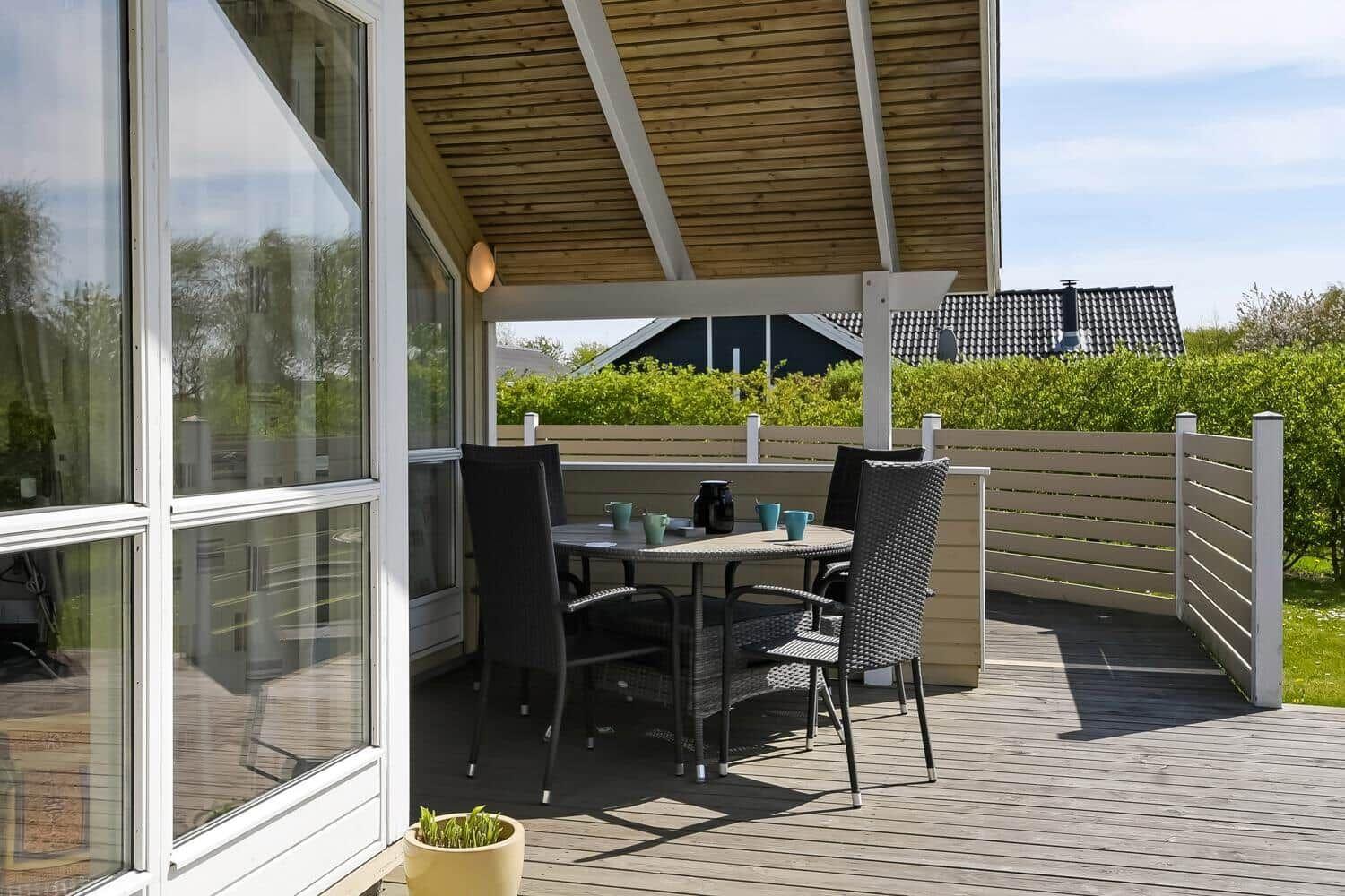 Terrasse mit Tisch und Stühlen unter Holzüberdachung