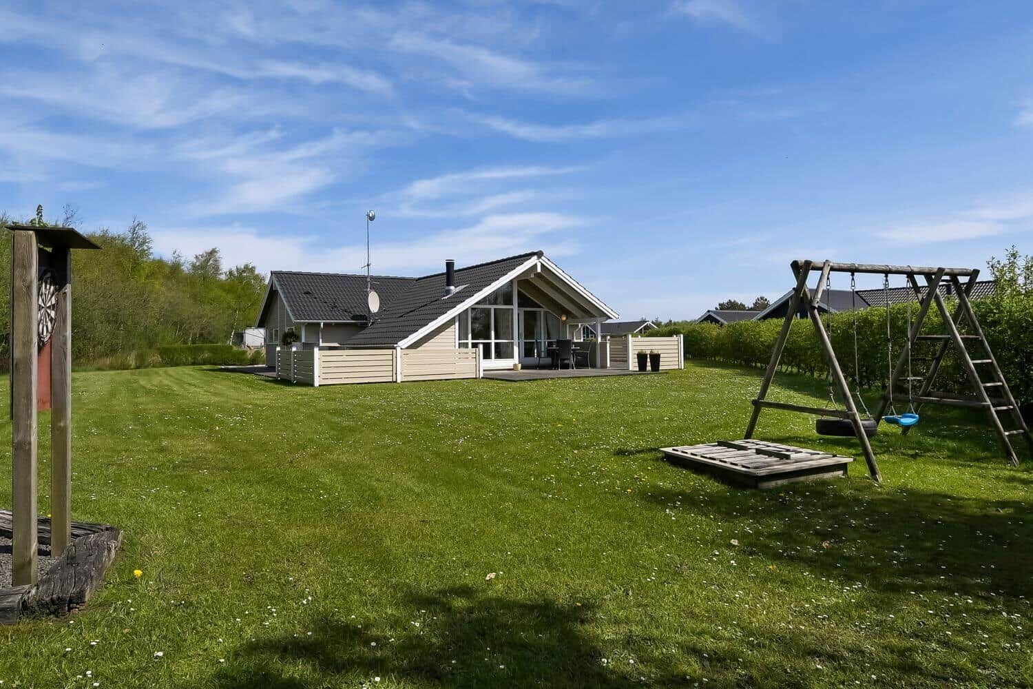 Haus mit großem Garten, Schaukel und Dartscheibe im Freien.
