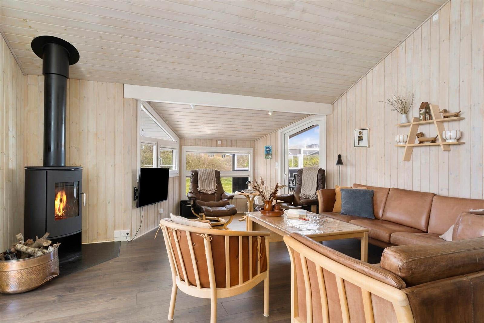 Wohnzimmer mit Holzwand, Kamin und Ledersofa.