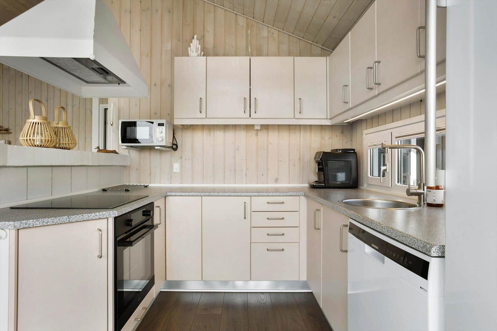 Küche mit Holzwand, weißen Schränken, Spüle und Edelstahlarmatur.