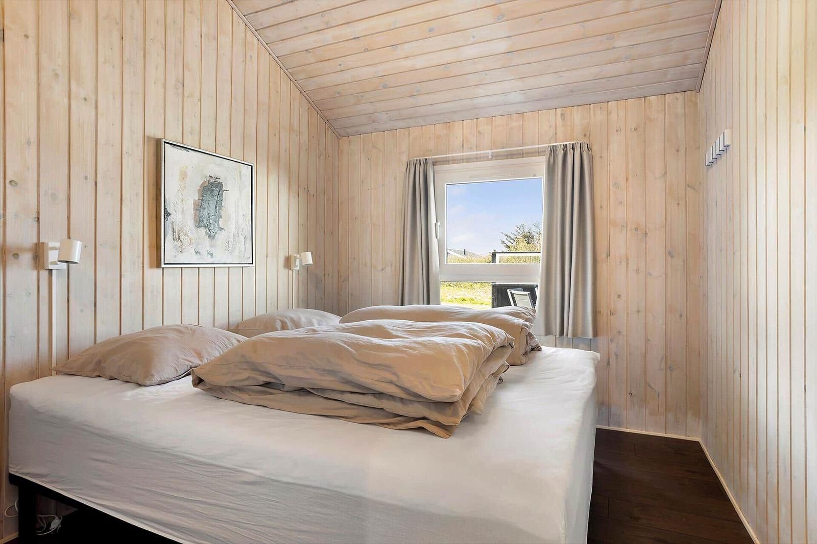 Schlafzimmer mit Holzwand, Bett und Fenster mit Blick.