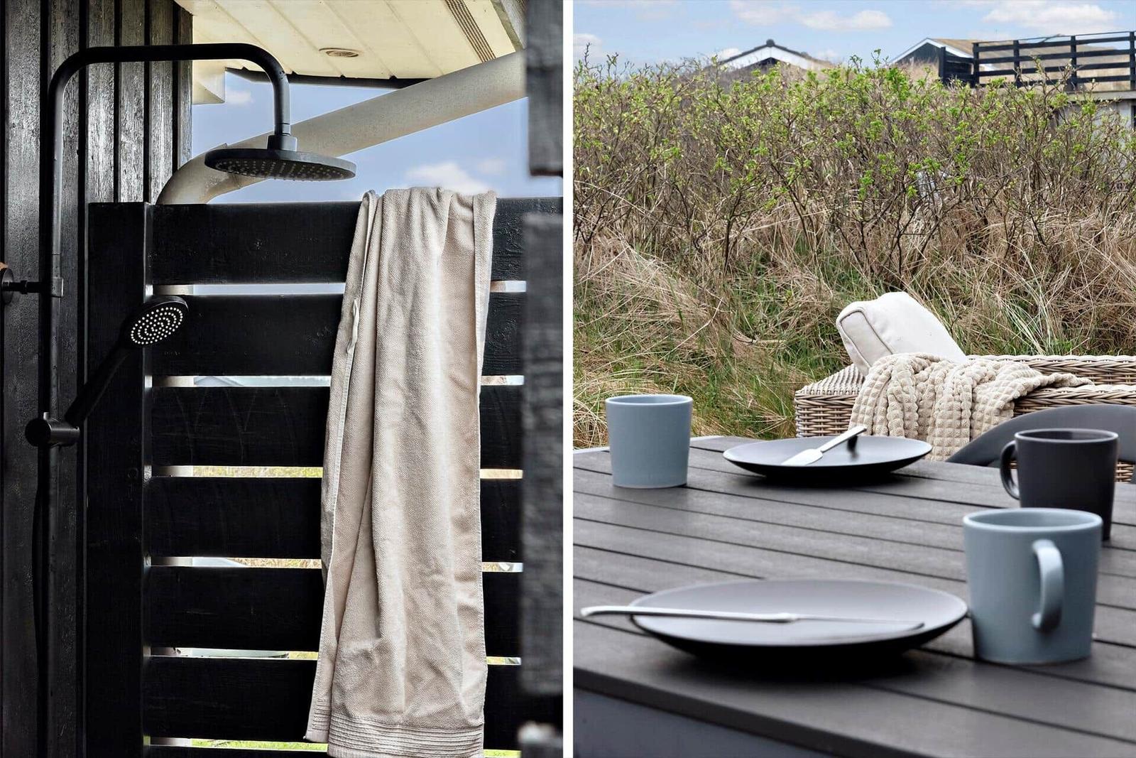 Außen-Dusche mit Hand- und Duschkopf. Terrasse mit Tisch, Stühlen und Blick auf Gras.