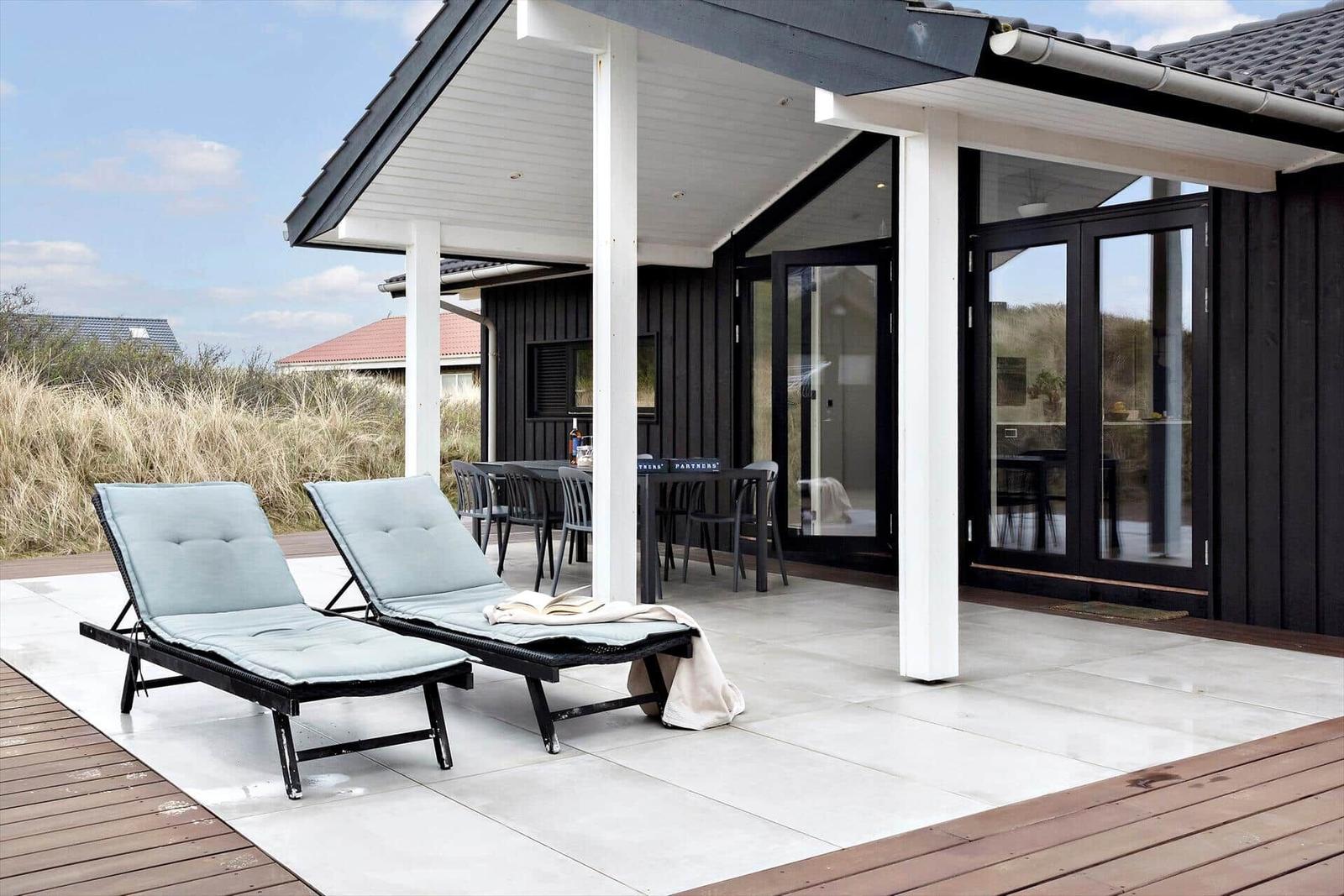 Terrasse mit Liegestühlen und Sitzgruppe unter Dach