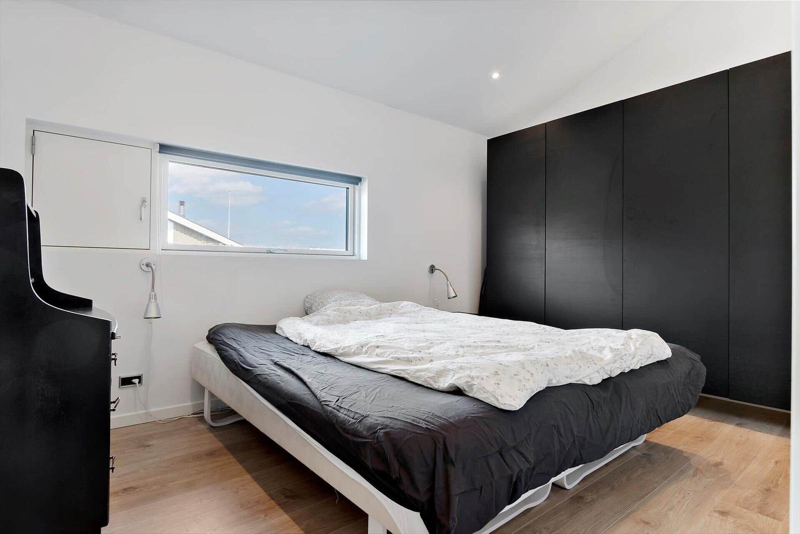 Schlafzimmer mit Bett, Kleiderschrank und Fenster.