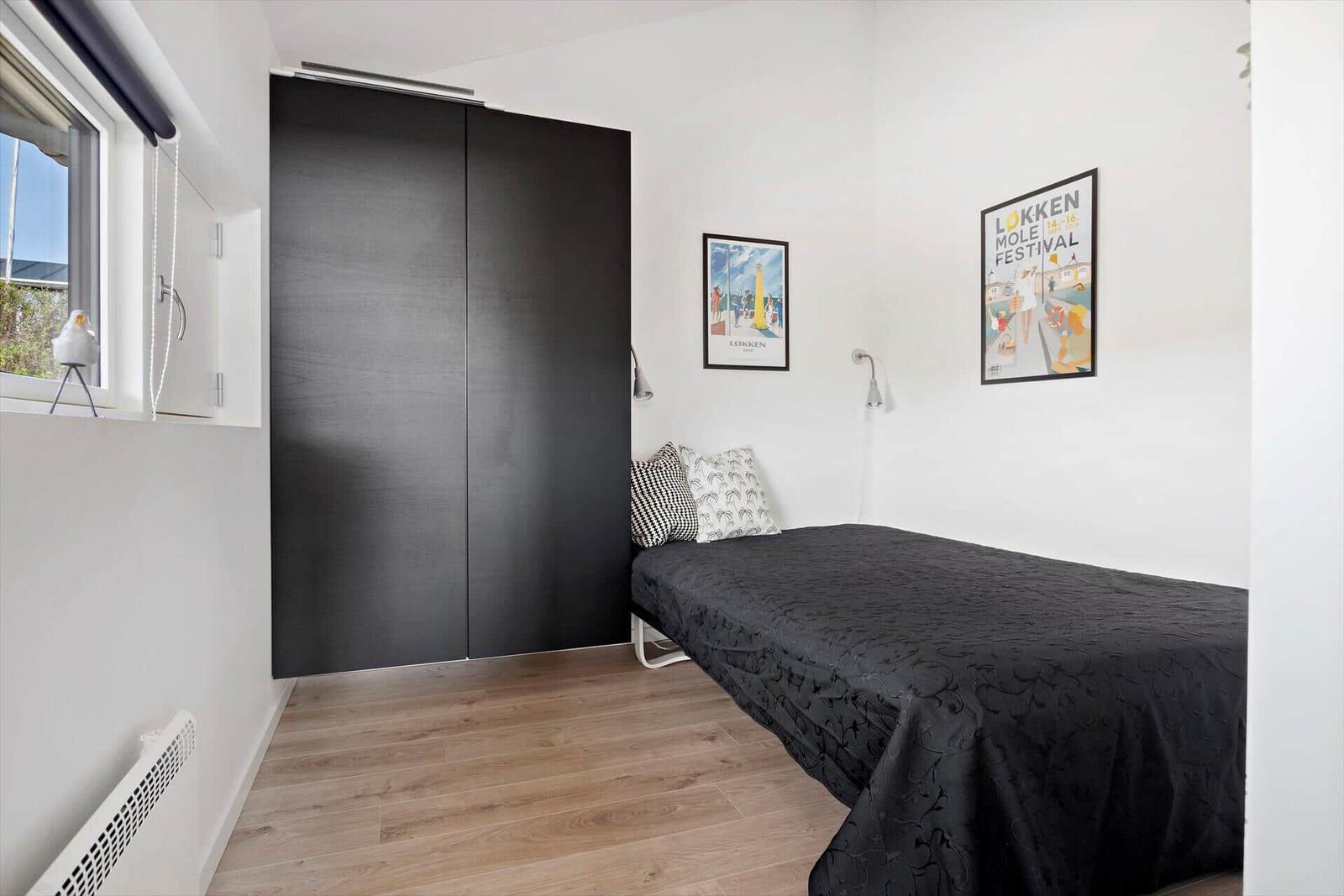Schlafzimmer mit Bett, Kleiderschrank und Fenster