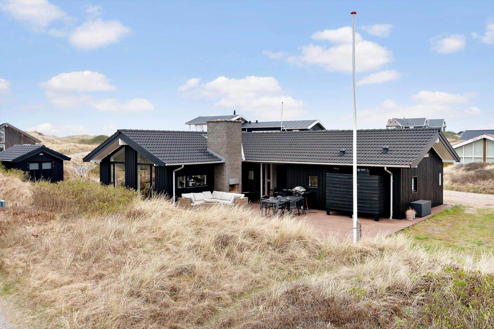 Moderne Strandhaus mit Terrasse, Grill und Sitzgelegenheit. Umgeben von Dünen.
