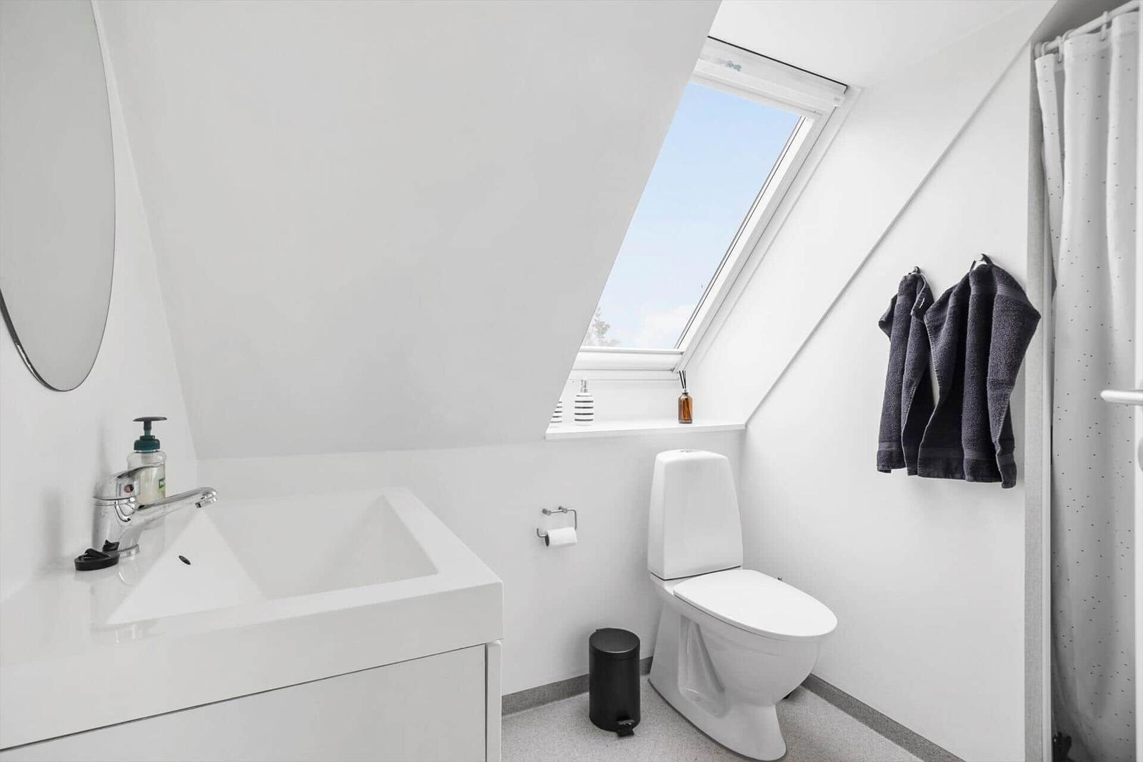 Badezimmer mit Dusche, Toilette und Waschbecken unter Dach