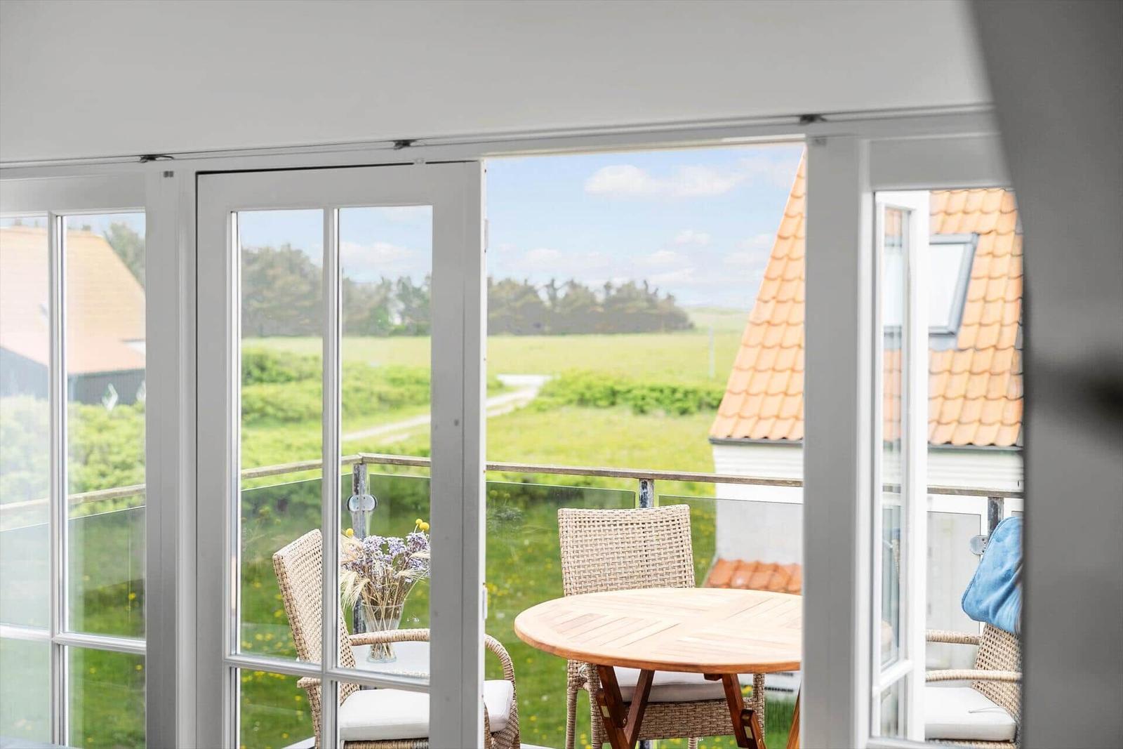 Terrasse mit Tisch und Stühlen bietet Blick auf grüne Landschaft.