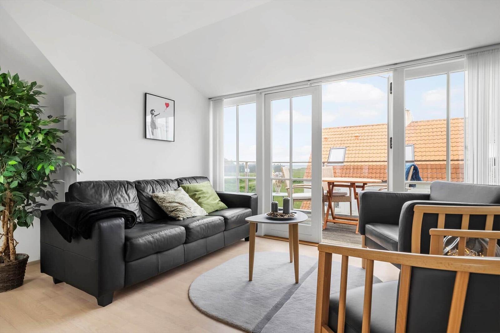 Wohnzimmer mit Sofa, Tisch und Balkon mit Sitzgelegenheiten.
