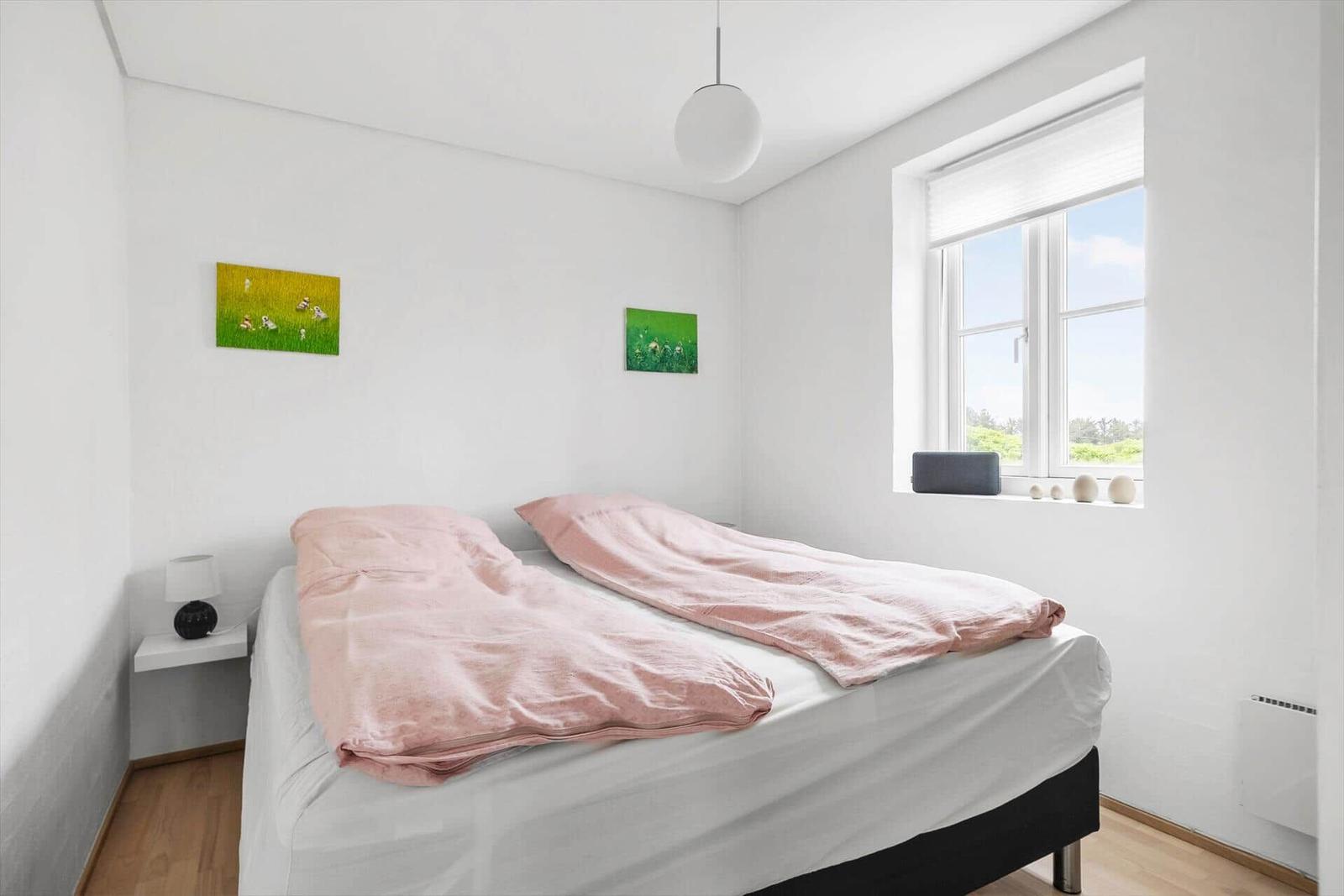 Schlafzimmer mit Bett, Fenster und Wandbildern