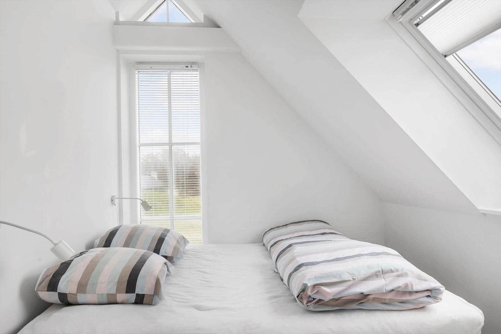 Dachgeschosszimmer mit Bett, Fenster und Dachfenster.