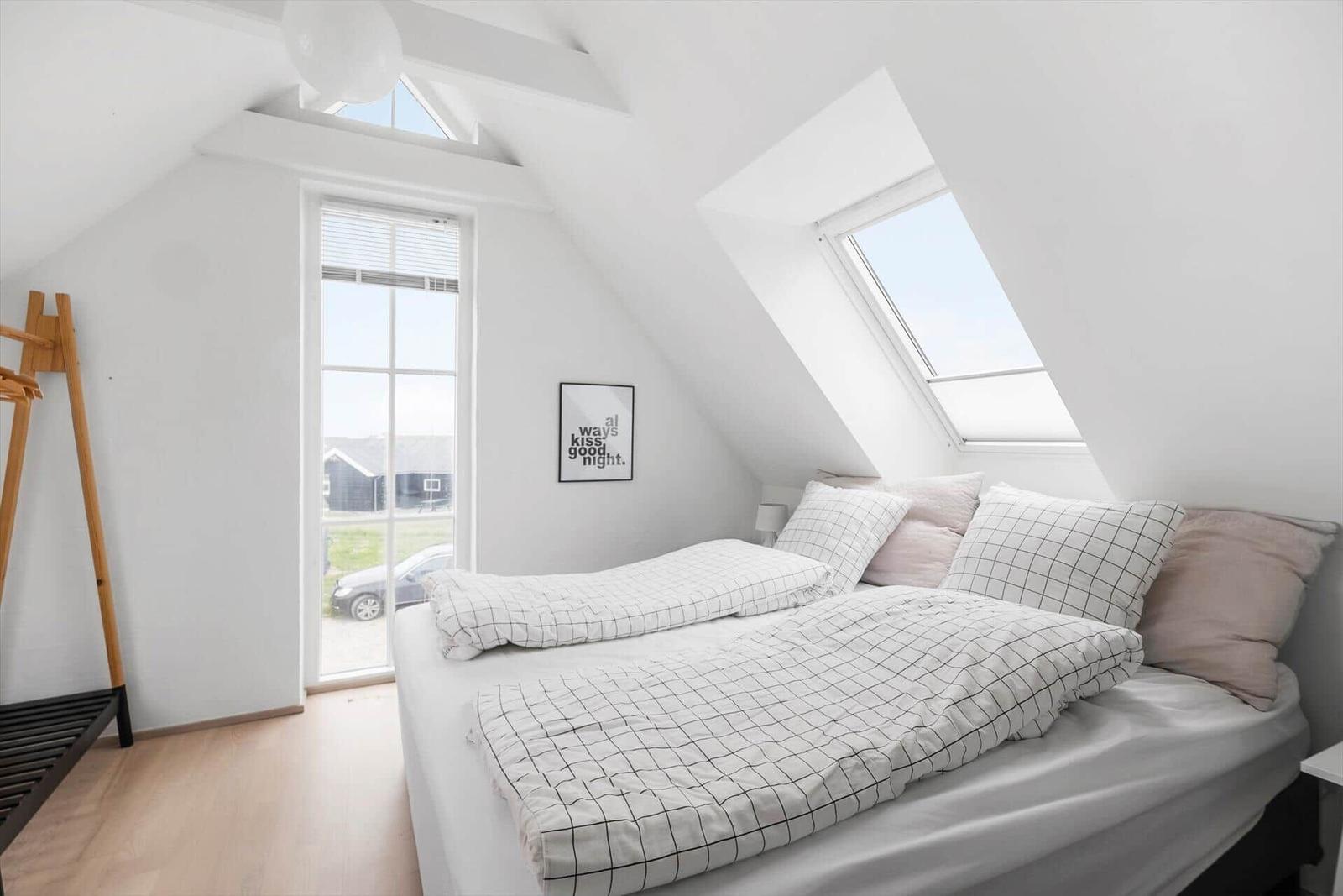 Schlafzimmer mit Dachschrägen, Dachfenster und Bett mit Kissen.