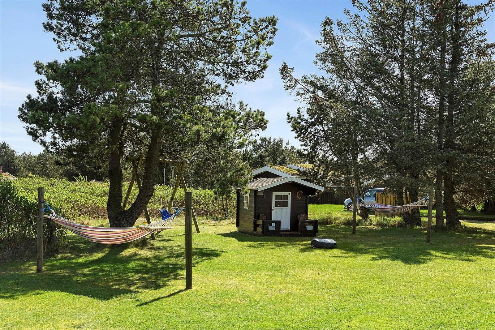 Haus mit grünem Rasen, Hängematten und Bäumen im Hintergrund.