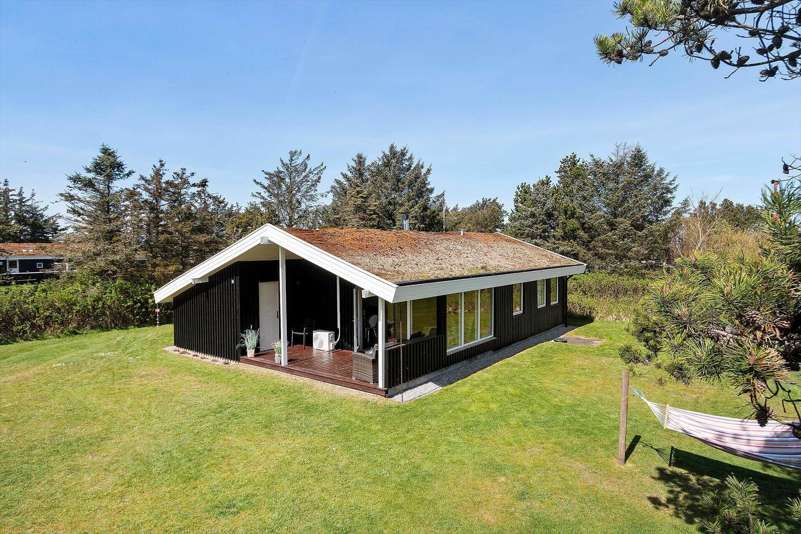 Moderne Holzhütte mit Terrasse und Garten. Hängem施cke im Vordergrund.