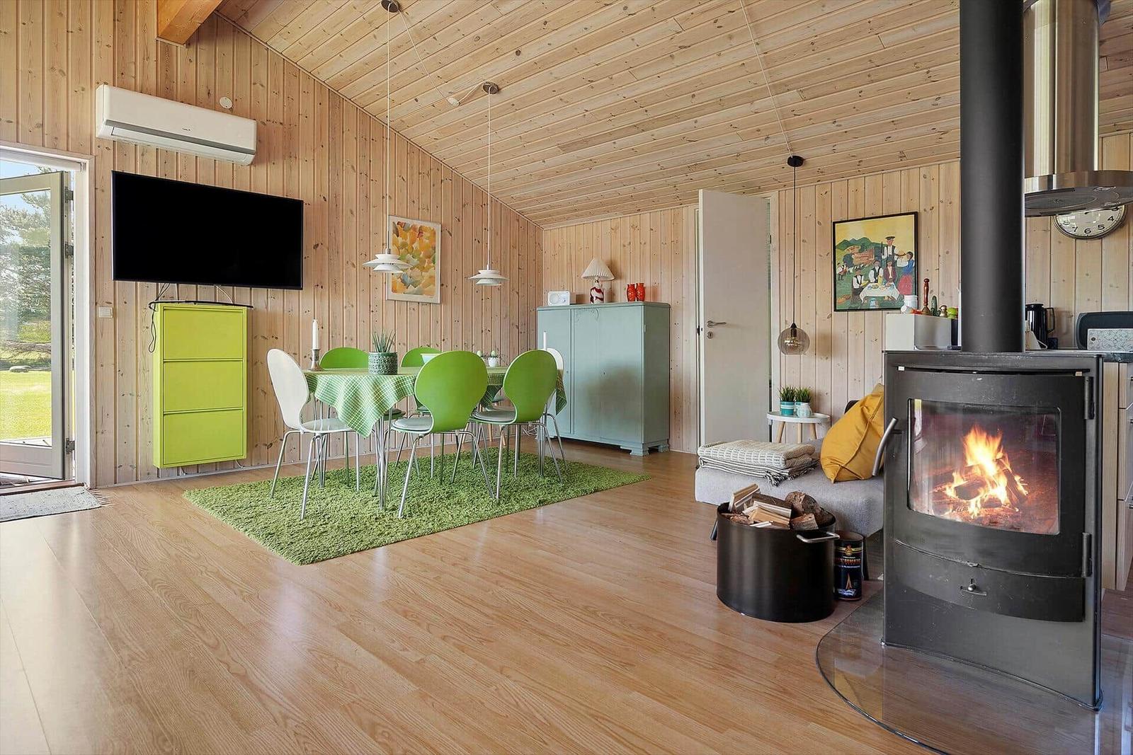 Wohnzimmer mit Kamin, Esstisch und TV. Holzwände und -boden.