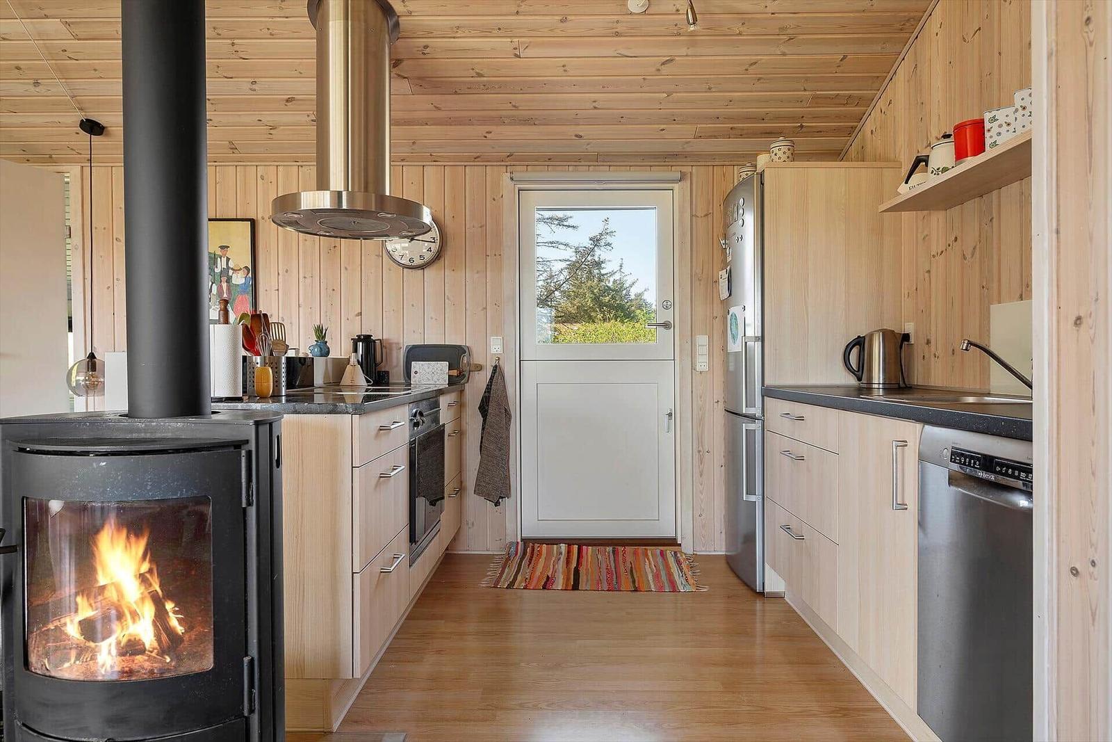 Küche mit Holzwand, Kaminofen und Küchenzeile