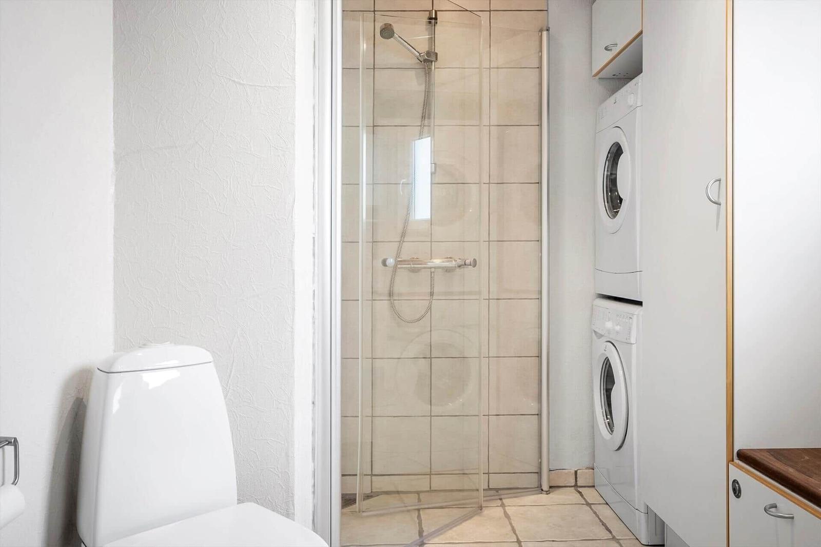 Bad mit Dusche, Toilette und Waschmaschine-Trockner-Kombination.