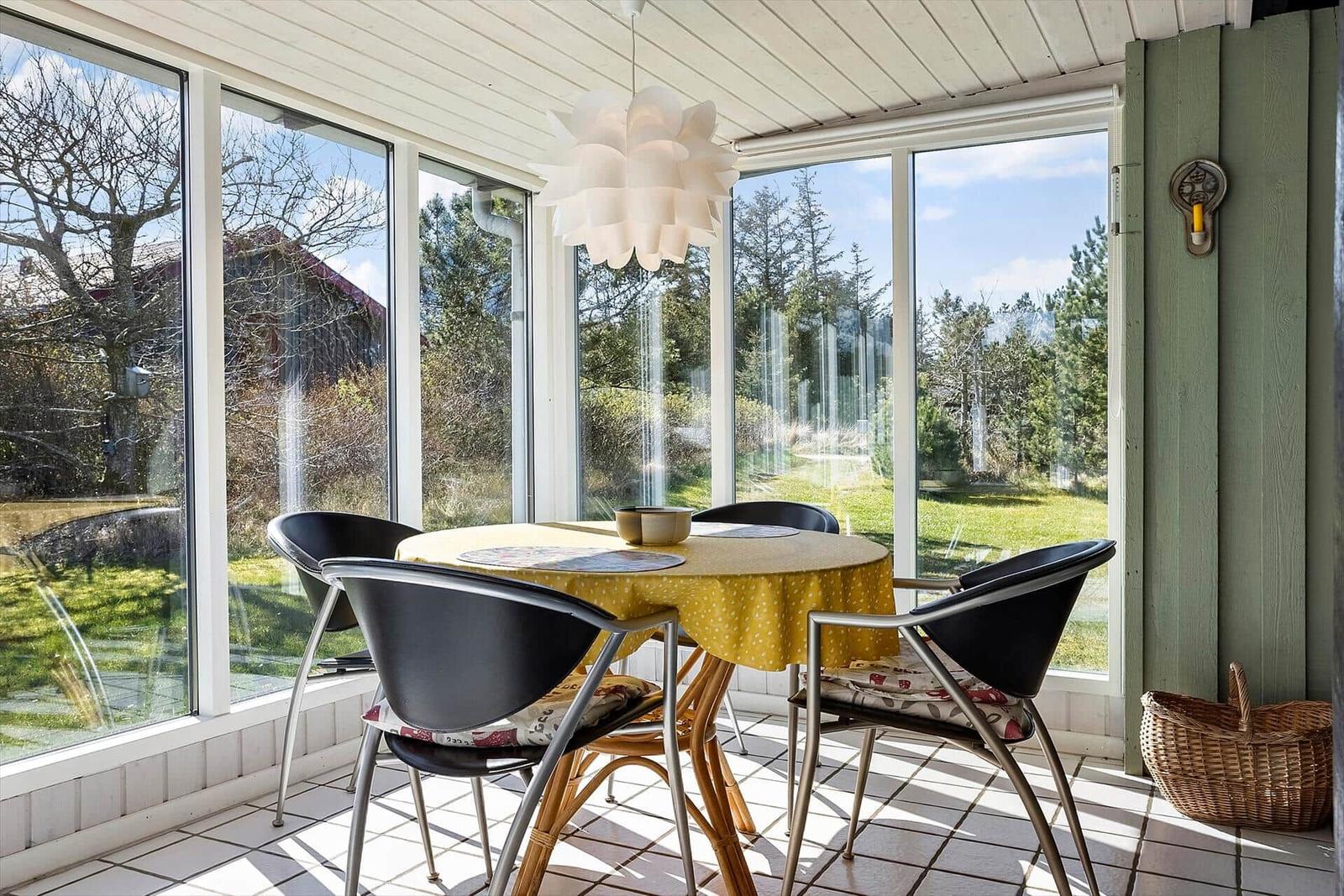 Glashalle mit Esstisch, Stühlen und Blick auf Garten