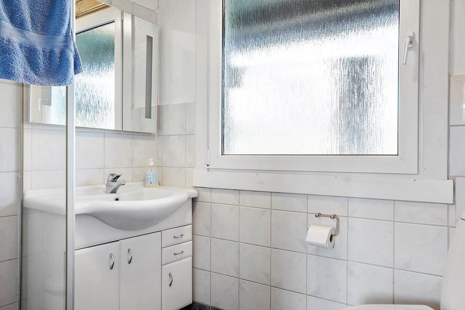 Badezimmer mit Waschbecken, Spiegelschrank und Fenster mit beschichtetem Glas.