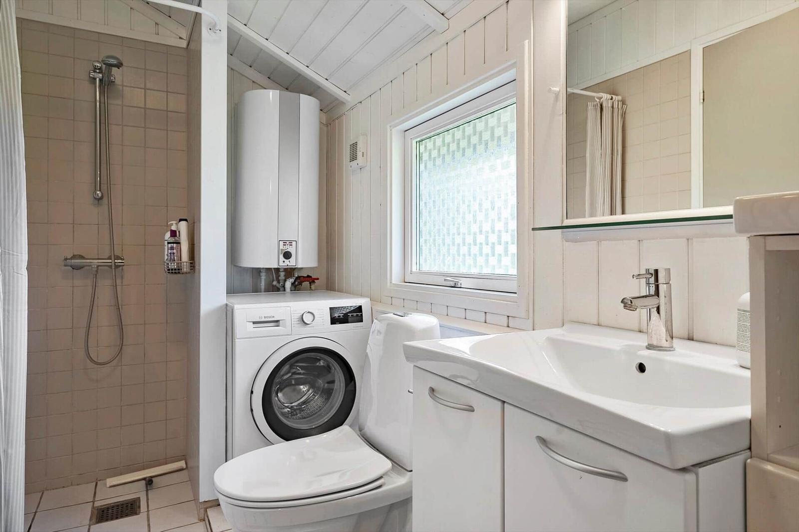 Badezimmer mit Dusche, Waschmaschine, WC und Waschbecken.