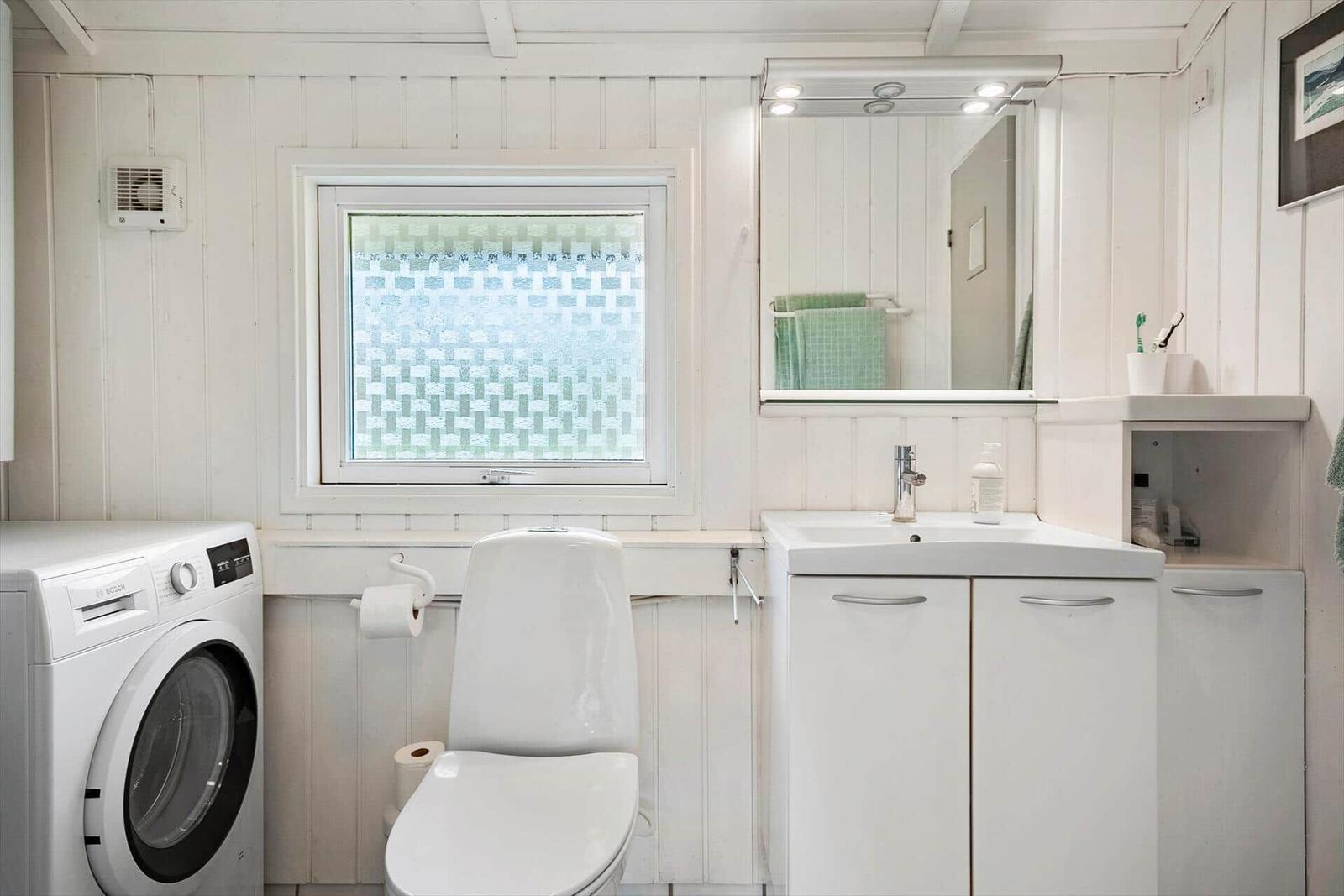 Badezimmer mit Waschmaschine, Toilette und Spiegel