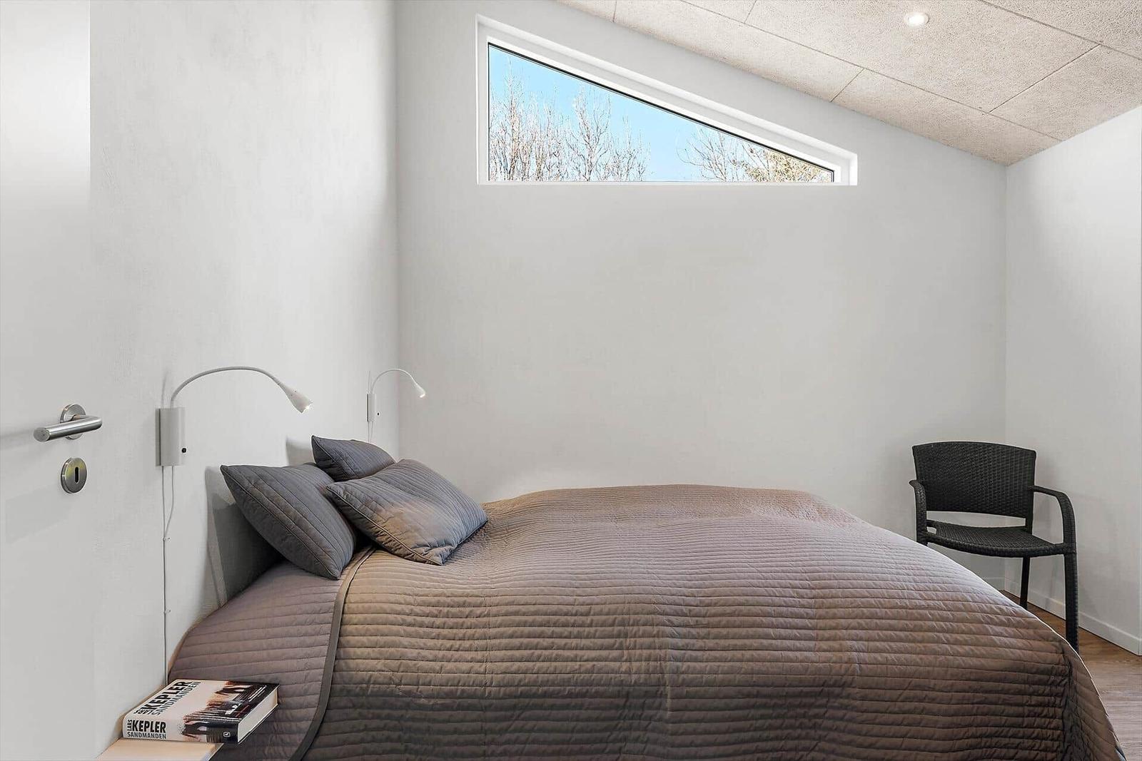Schlafzimmer mit Bett, Stuhl und schmalen Fenster.