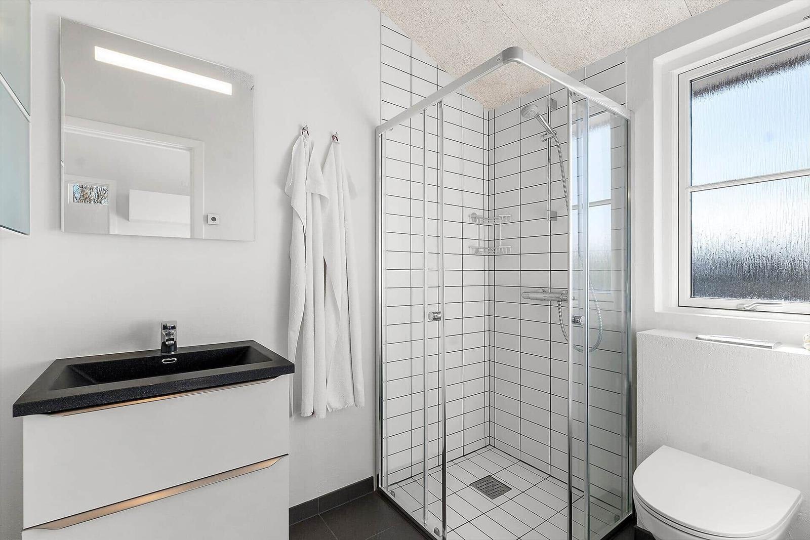 Badezimmer mit Dusche, Waschbecken und Toilette.