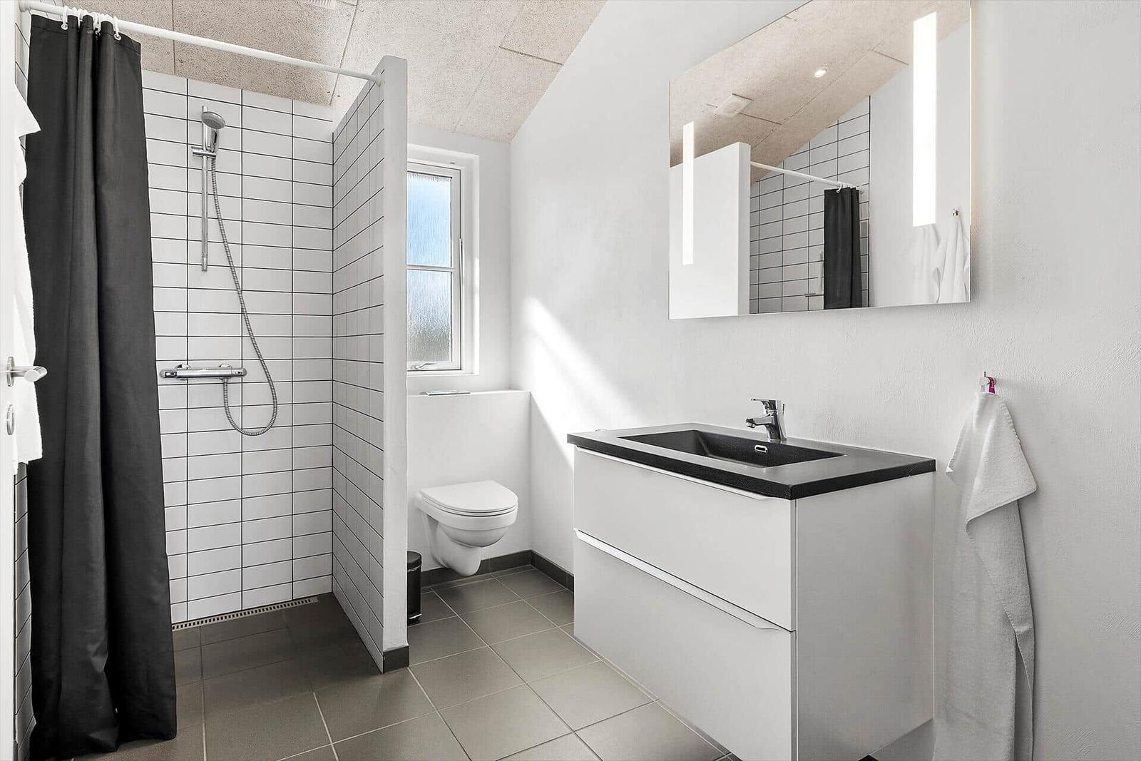Badezimmer mit Dusche, Toilette und Waschbecken mit Spiegel